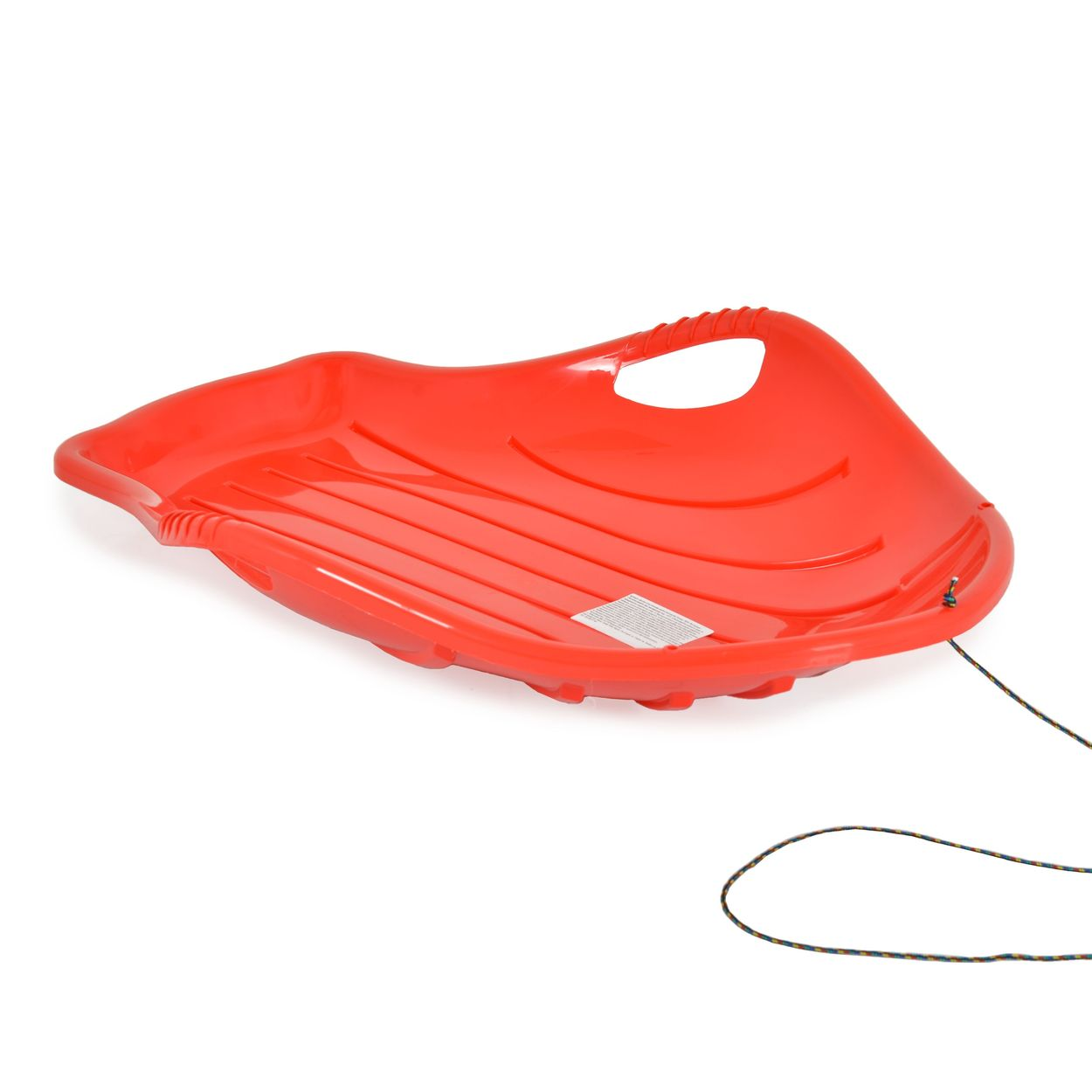 Ein roter Plastikschlitten mit Griff und Seil liegt auf weißem Grund. Der Schlitten hat Rillen und ein Etikett.