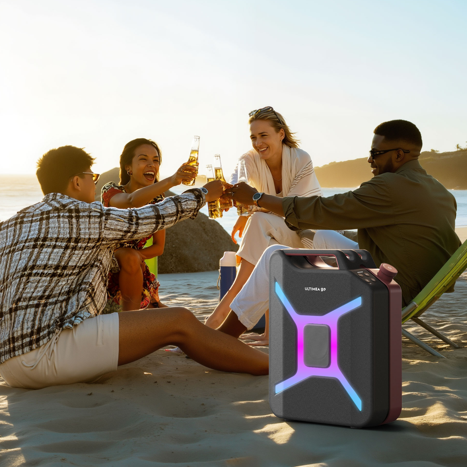 Cztery osoby wznoszą toasty butelkami piwa na plaży, głośnik na pierwszym planie. Słońce zachodzi w tle.