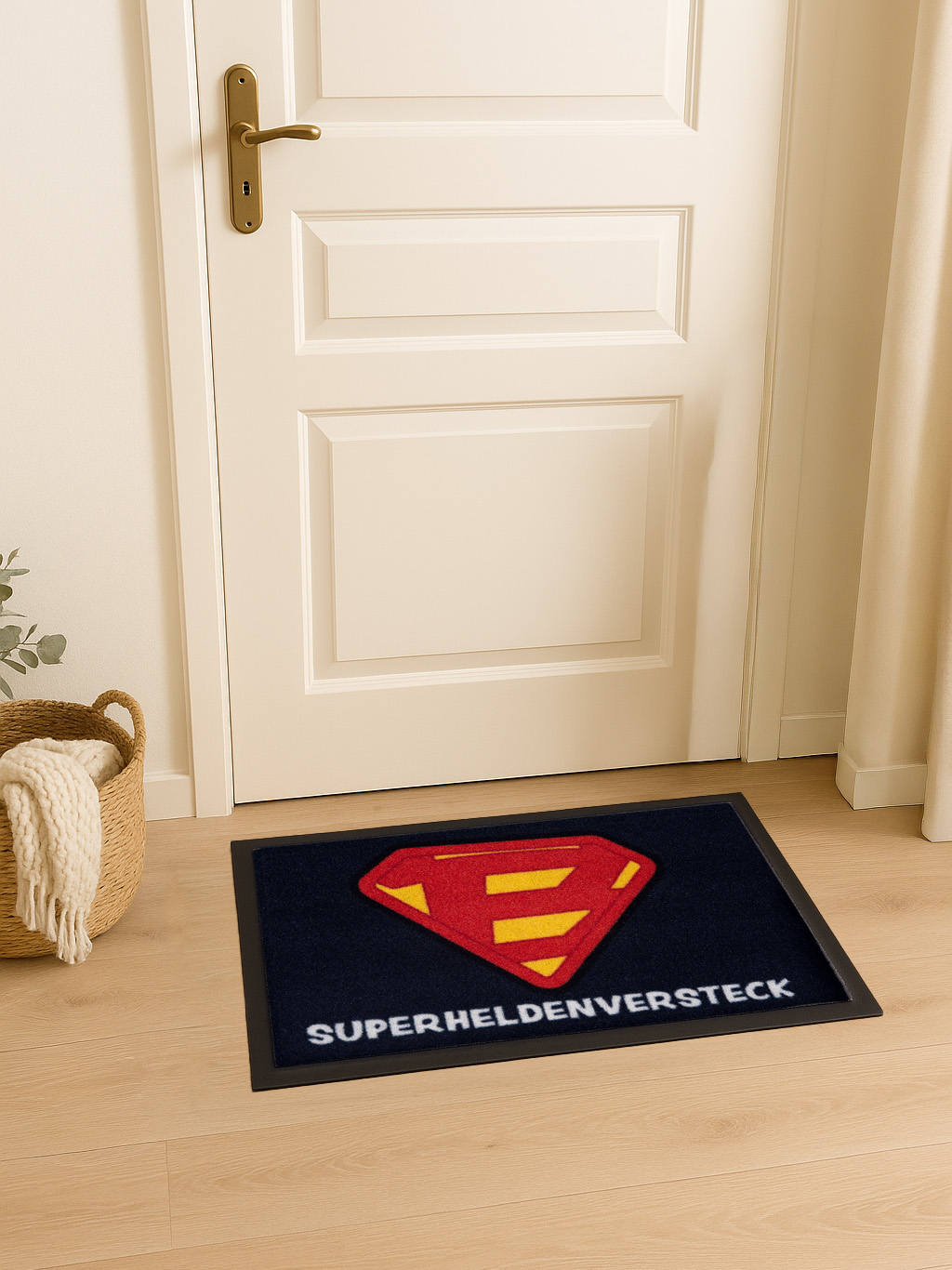 Eine Fußmatte mit Superman-Logo vor einer weißen Tür. Links ein Korb mit einer Decke.
