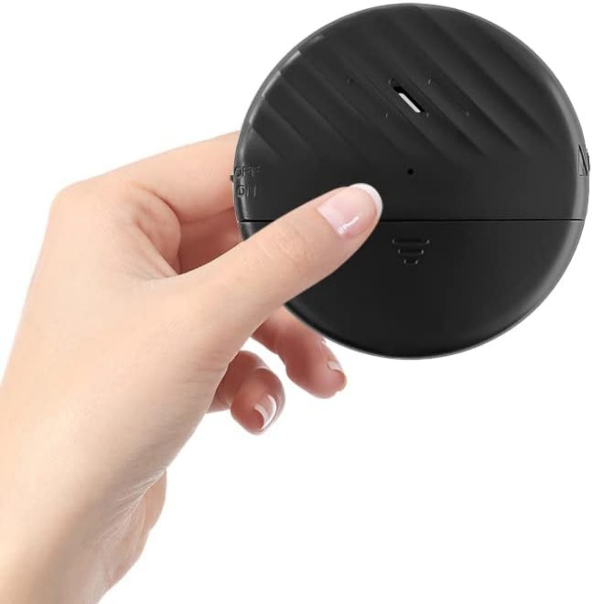 Eine Hand hält ein schwarzes, rundes Gerät. Das Gerät hat Rillen und eine kleine Öffnung. Die Hand hat gepflegte Nägel.