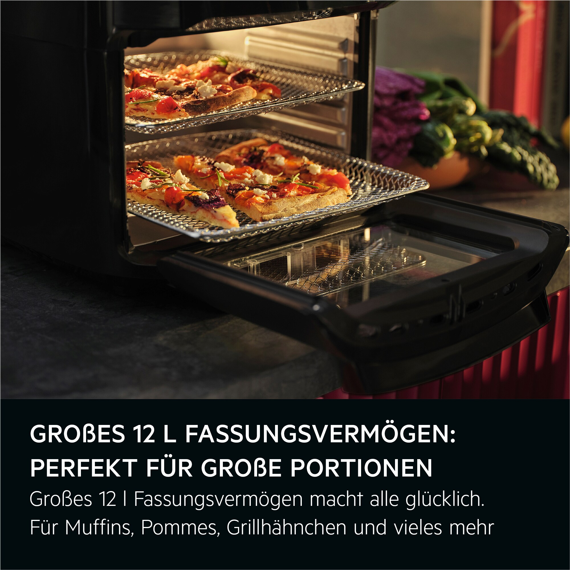 Ein Airfryer mit Pizza auf Racks. Die offene Tür zeigt das Innere. Gemüse ist im Hintergrund.