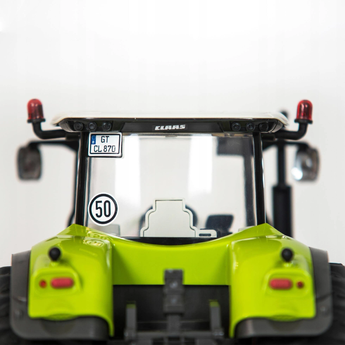 Primer plano de un tractor verde. Tiene una matrícula, una señal de límite de velocidad y luces rojas. La marca es CLAAS.