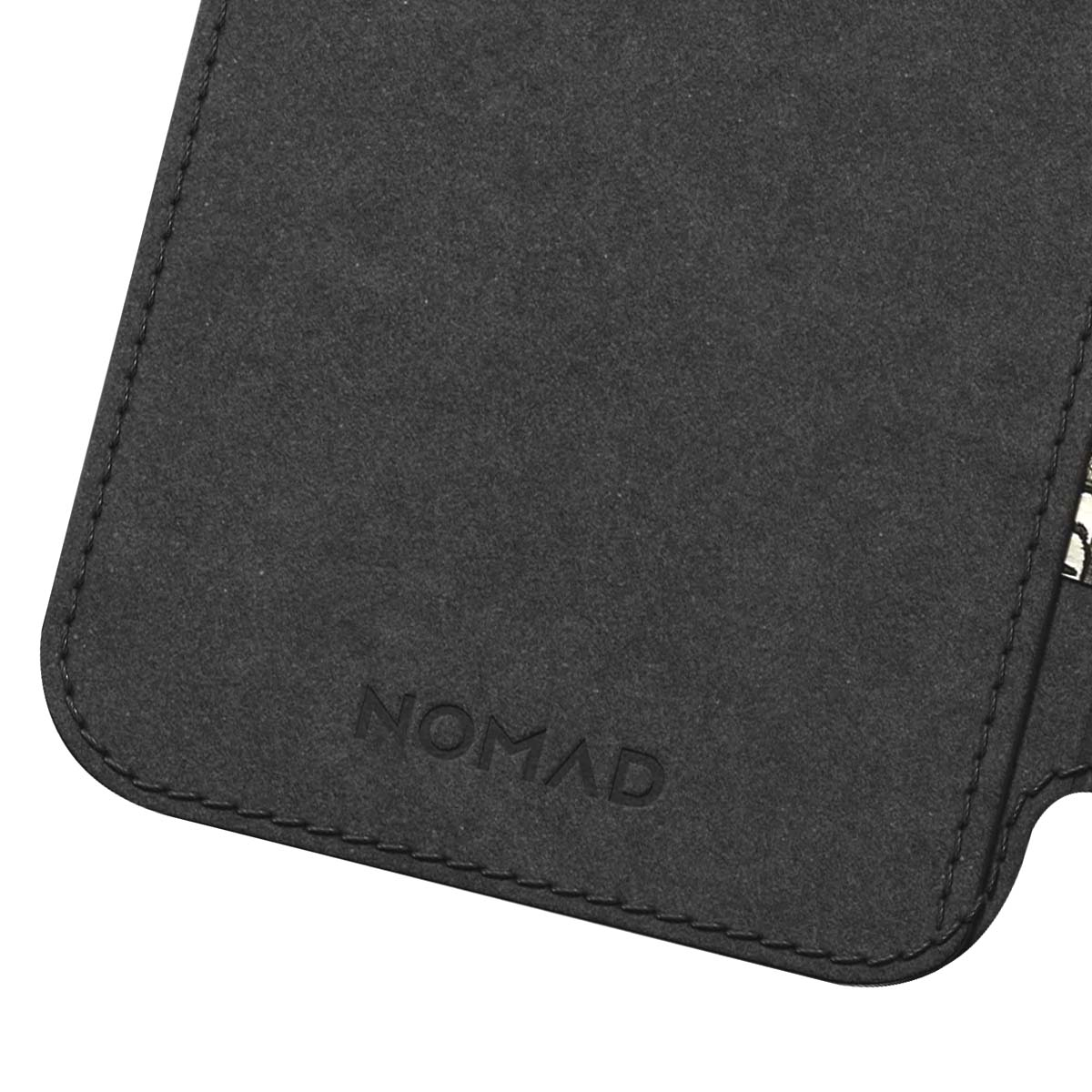 Primo piano di una custodia in pelle nera. La parola "NOMAD" è in rilievo. Le cuciture sono visibili sui bordi.