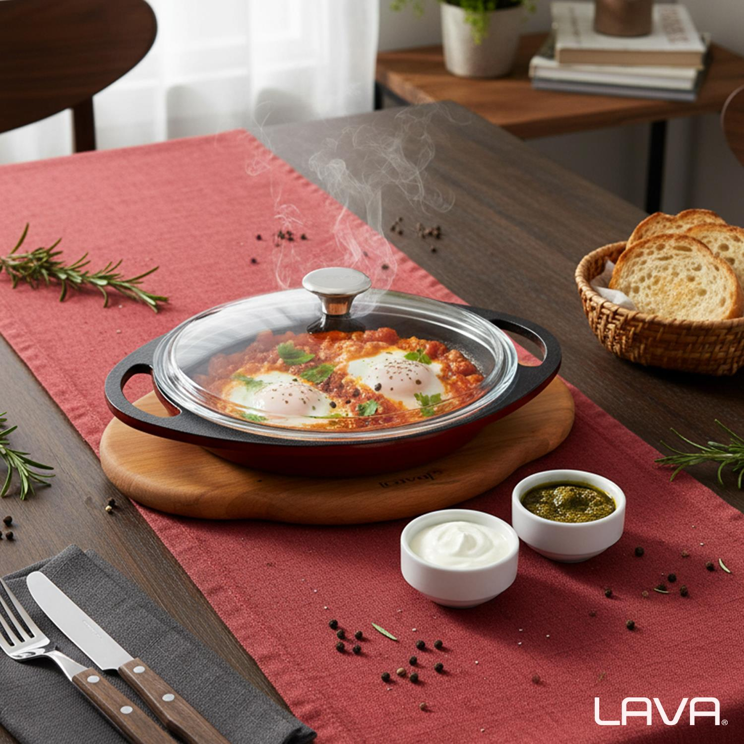 Kırmızı bir tavada, cam kapaklı, ahşap tahtada, ekmek ve soslarla servis edilen, domates soslu yumurta yemeği.