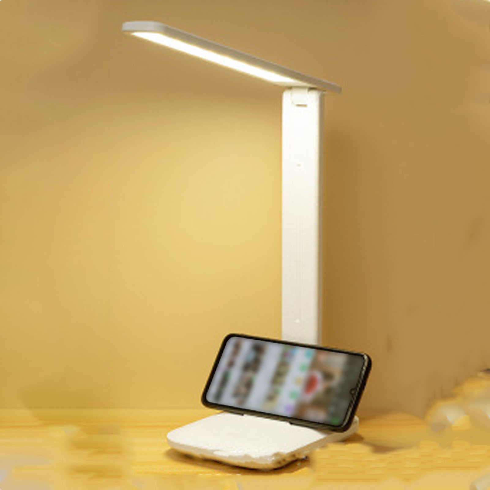 Eine weiße Schreibtischlampe mit einem Telefon auf einem weißen Ständer. Der Hintergrund ist eine gelbe Wand.