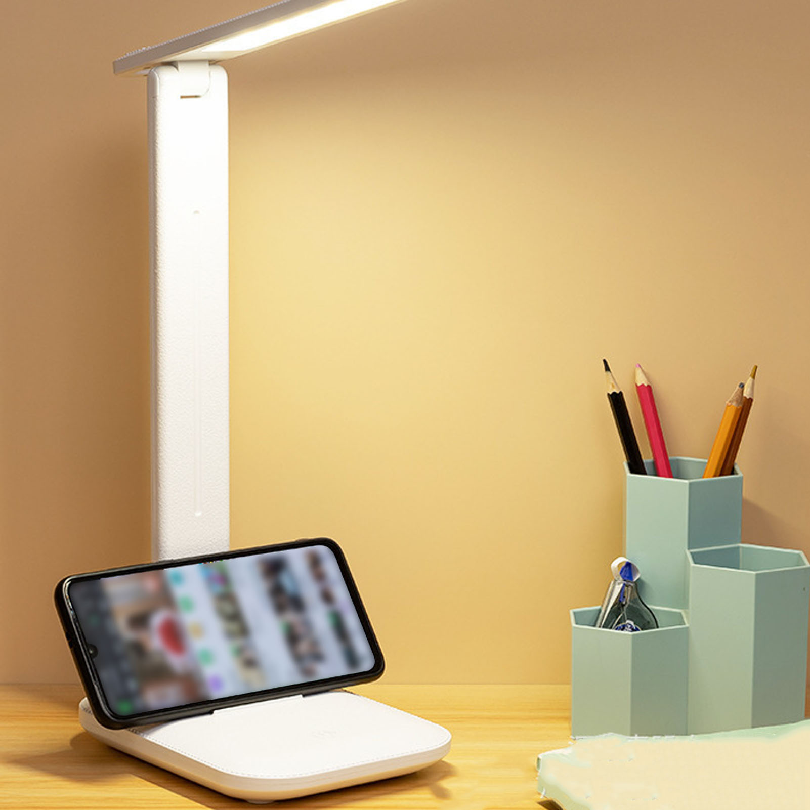 Ein Schreibtisch mit Lampe, Telefon auf Ladegerät und Stifthalter. Der Hintergrund ist ein sanftes Gelb.