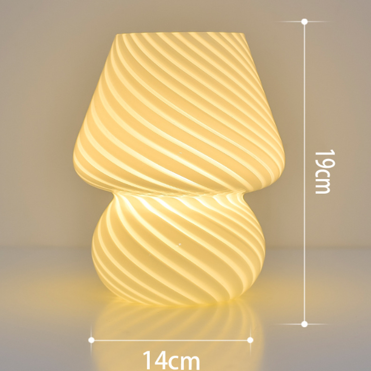 Eine pilzförmige Lampe mit Wirbelglasdesign. Sie ist 19 cm hoch und 14 cm breit und strahlt ein warmes, weiches Licht aus.