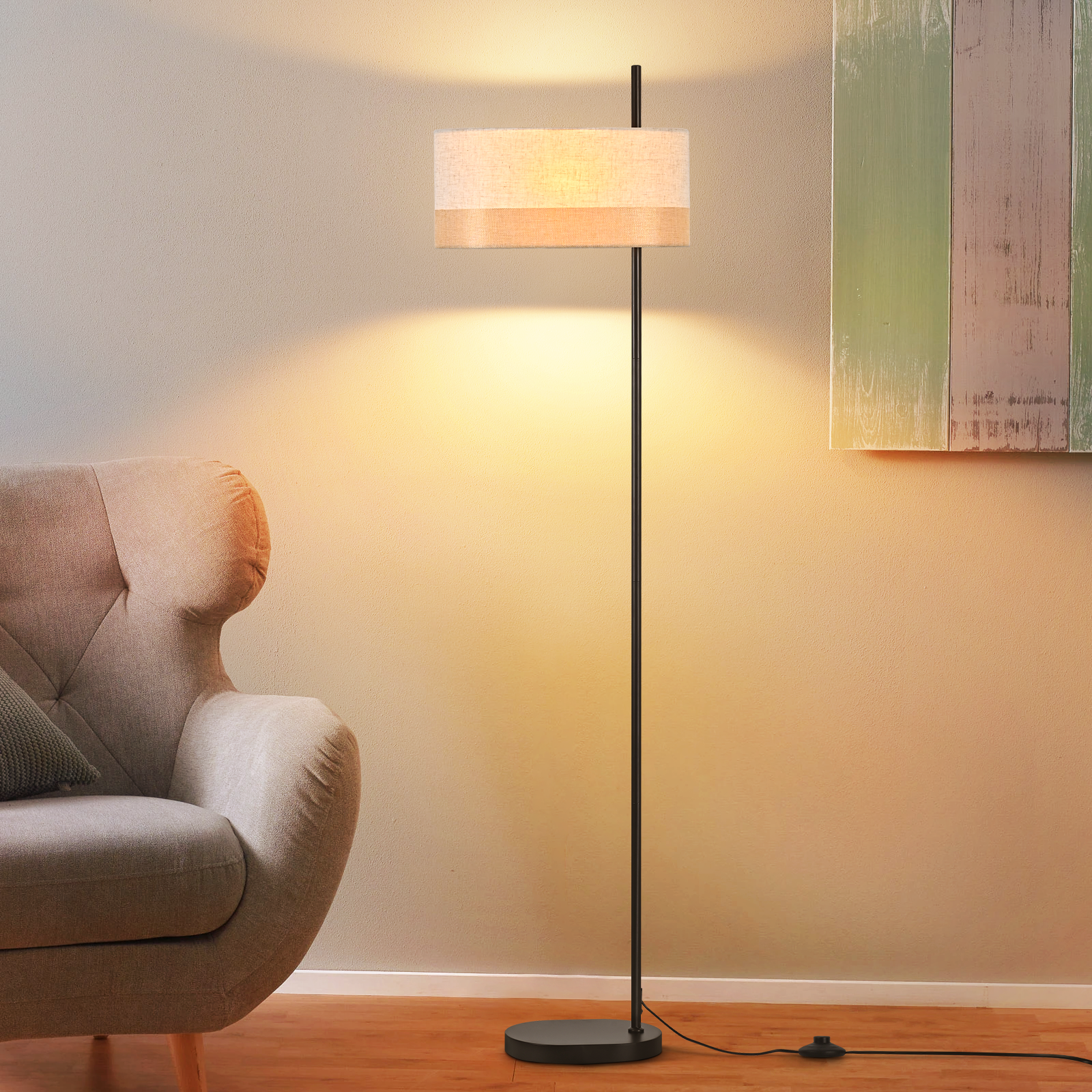 Una lampada da terra con paralume beige, una poltrona grigia e una decorazione murale in legno colorato. Luce calda.