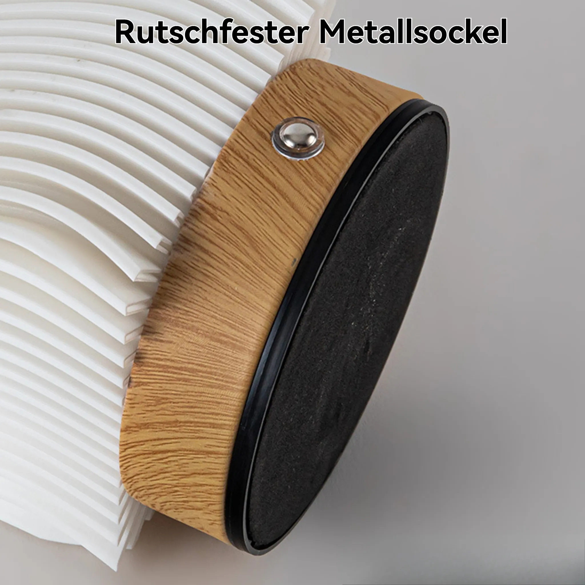 Nahaufnahme eines Holzgriffs mit schwarzem Pad und silbernem Knopf neben einem weißen, gerippten Objekt.