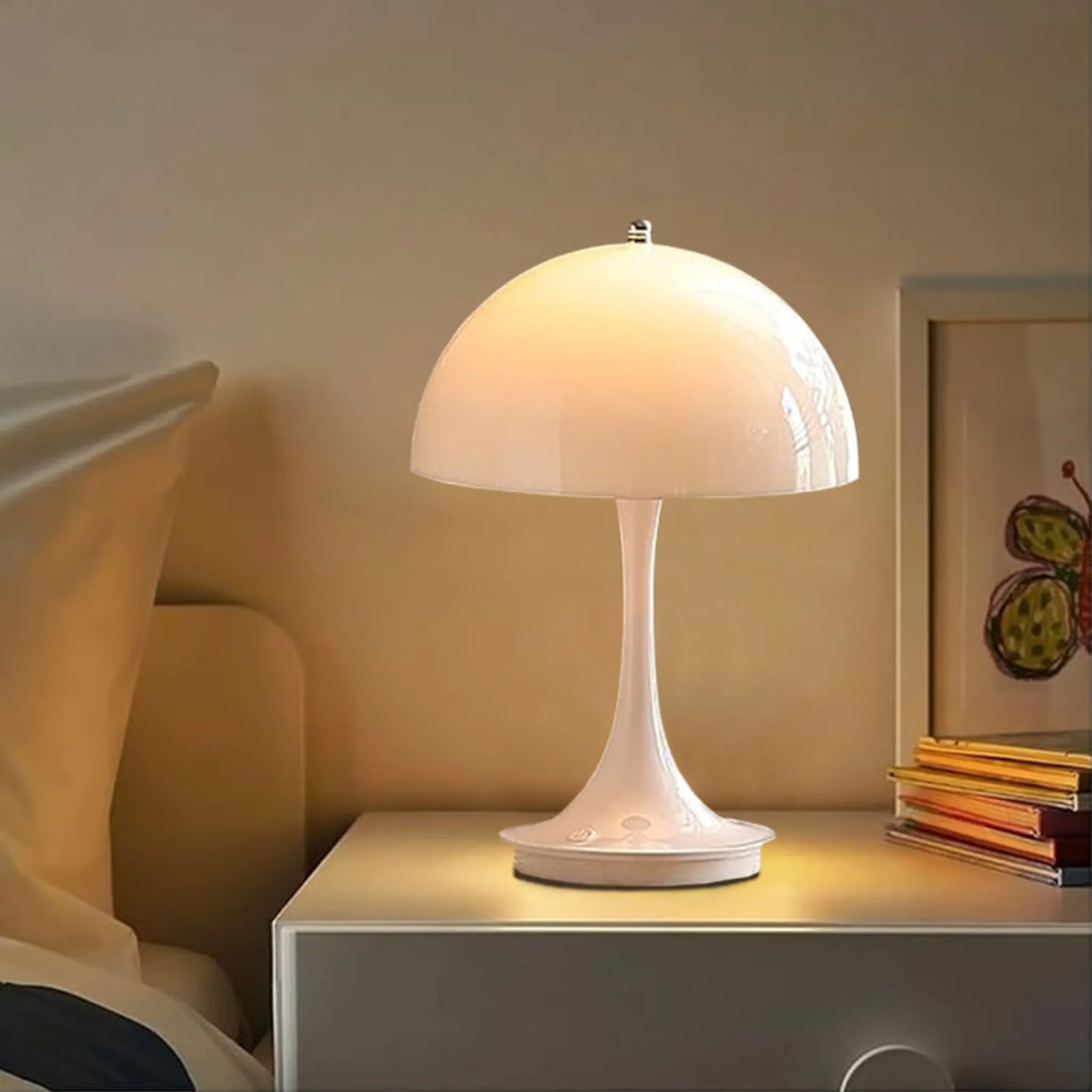 Eine weiße Pilzlampe auf einem Nachttisch. Eine Zeichnung eines Schmetterlings ist sichtbar. Ein Bett und Bücher sind ebenfalls vorhanden.