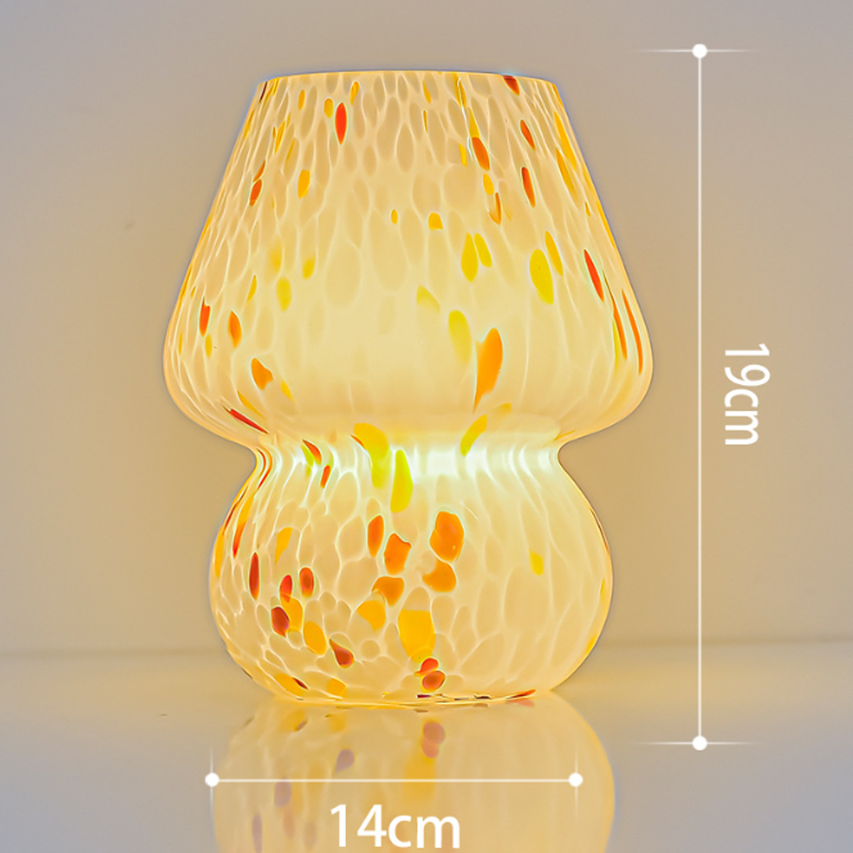 Eine pilzförmige Glaslampe mit gelben und orangen Punkten. Die Lampe ist 19 cm hoch und 14 cm breit.