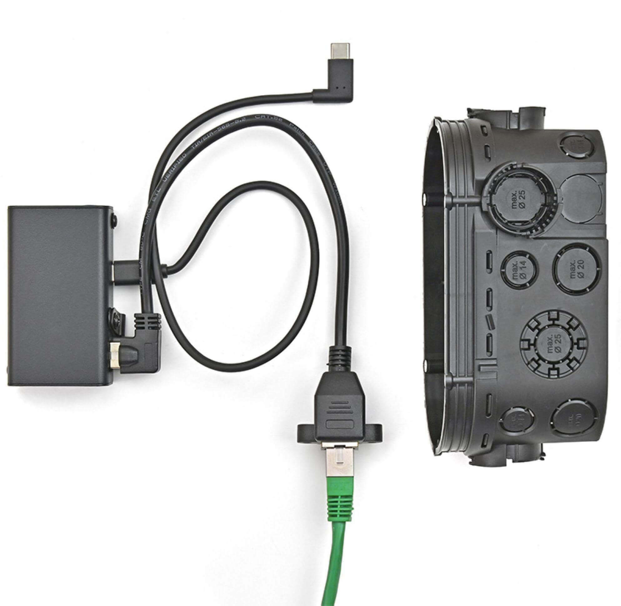Schwarze Box, schwarzes Kabel mit grünem Ethernet-Kabel und eine schwarze elektrische Anschlussdose mit kreisförmigen Öffnungen.