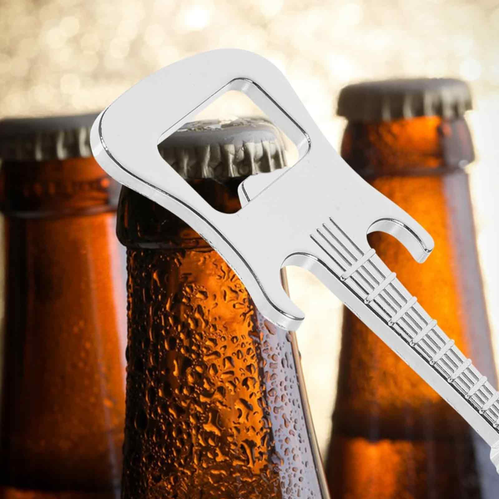 Ein gitarrenförmiger Flaschenöffner befindet sich auf einer Flasche. Zwei weitere braune Flaschen sind dahinter. Der Hintergrund ist verschwommen.