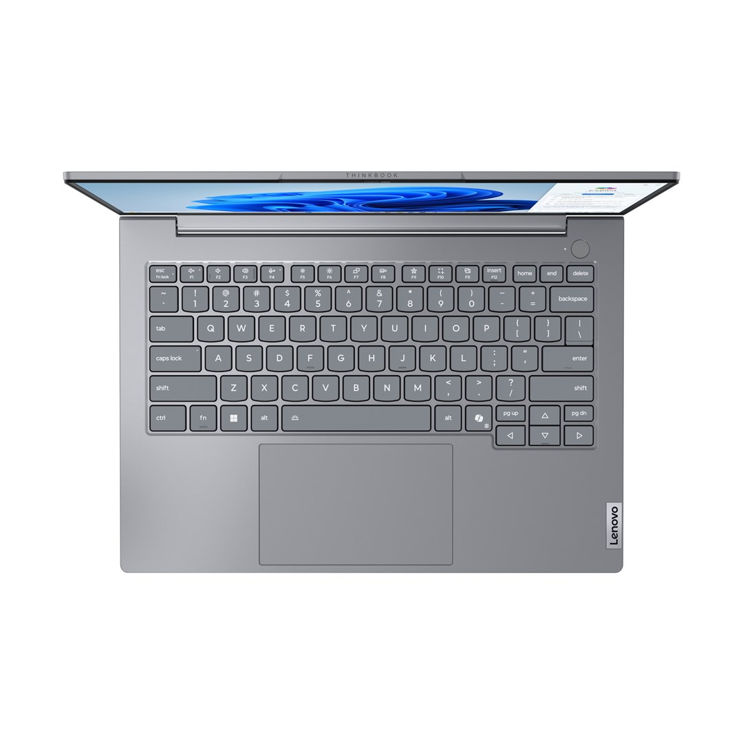 Szary laptop Lenovo ThinkBook jest otwarty. Widoczna klawiatura z różnymi klawiszami. Ekran wyświetla niebiesko-biały obraz.
