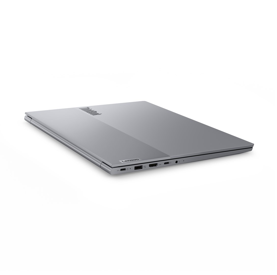 Zamknięty, srebrny laptop Lenovo ThinkBook na białej powierzchni. Widoczne logo Lenovo. Tło jest białe.