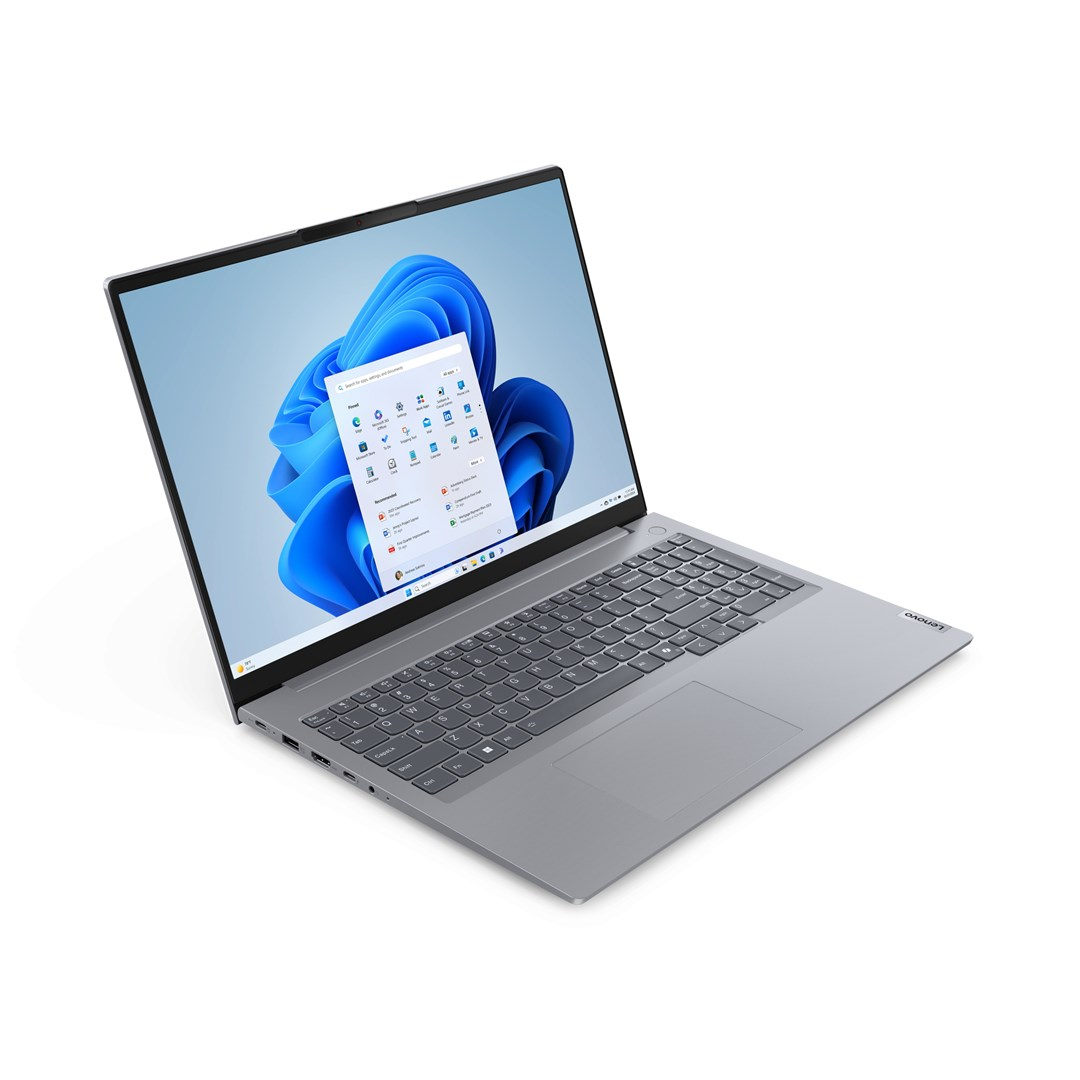 Laptop Lenovo jest otwarty, wyświetlając interfejs Windows 11. Ekran pokazuje pulpit z aplikacjami i niebieskim tłem.