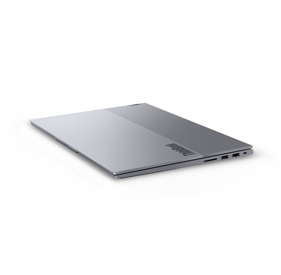 Zamknięty, srebrny laptop Lenovo ThinkBook na białym tle. Widoczne logo ThinkBook. Laptop jest lekko pochylony.