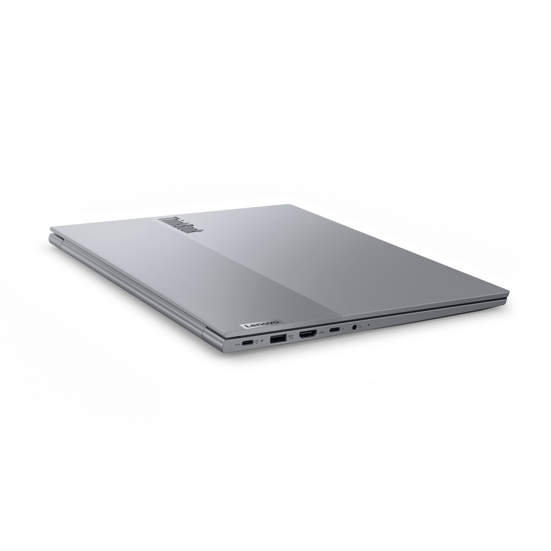 Zamknięty, srebrny laptop Lenovo ThinkBook leży na białej powierzchni. Widoczne jest logo Lenovo. Logo ThinkBook znajduje się u góry.