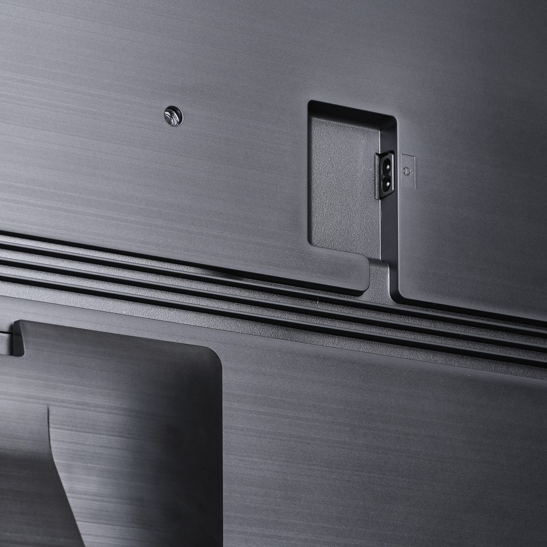 Zbliżenie na tył ciemnoszarego telewizora z portami zasilania i innymi. Powierzchnia ma szczotkowaną metalową teksturę.