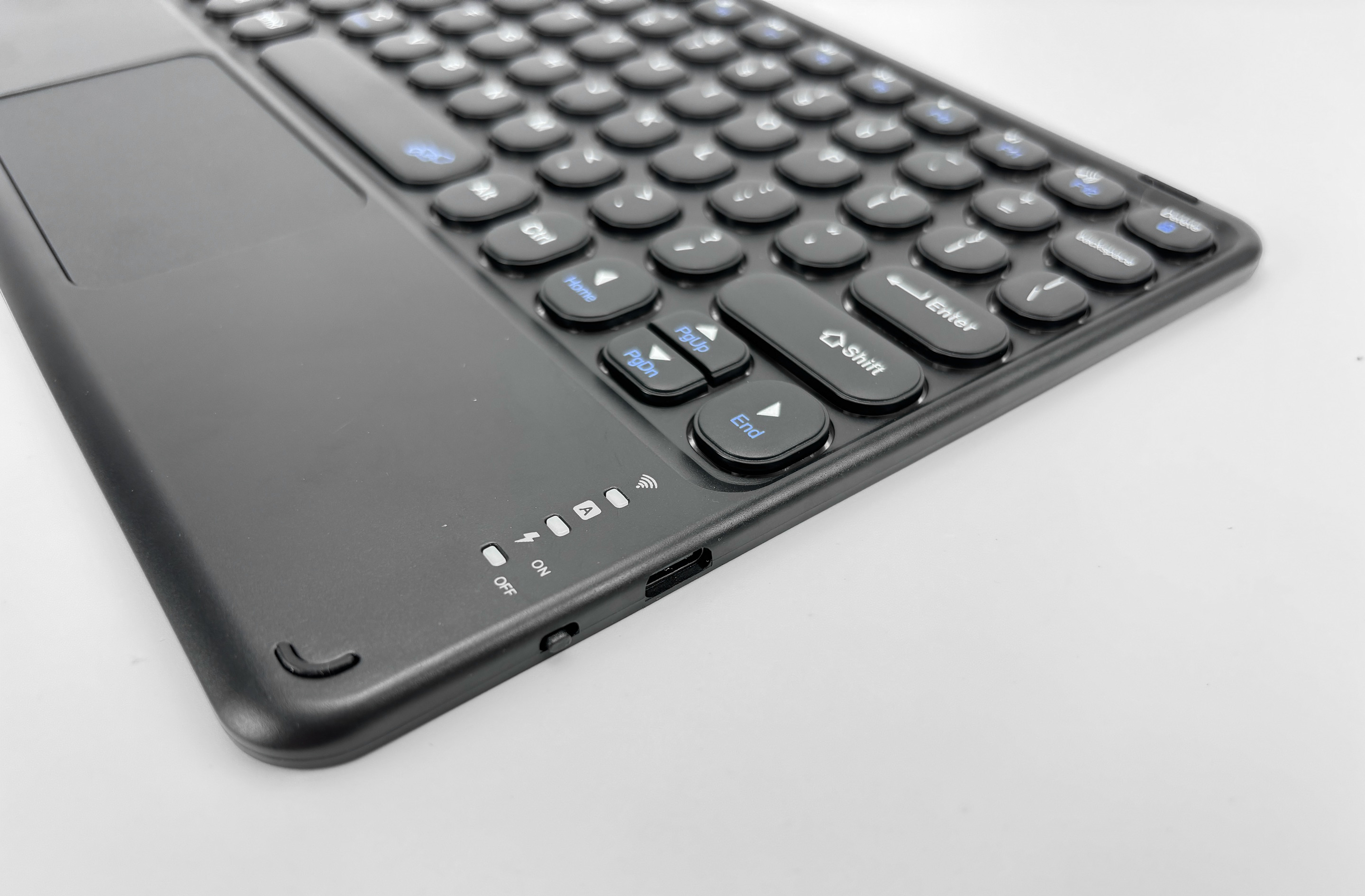 Eine schwarze Tastatur mit Touchpad liegt auf einer weißen Oberfläche. Tasten sind schwarz mit weißer Beschriftung.