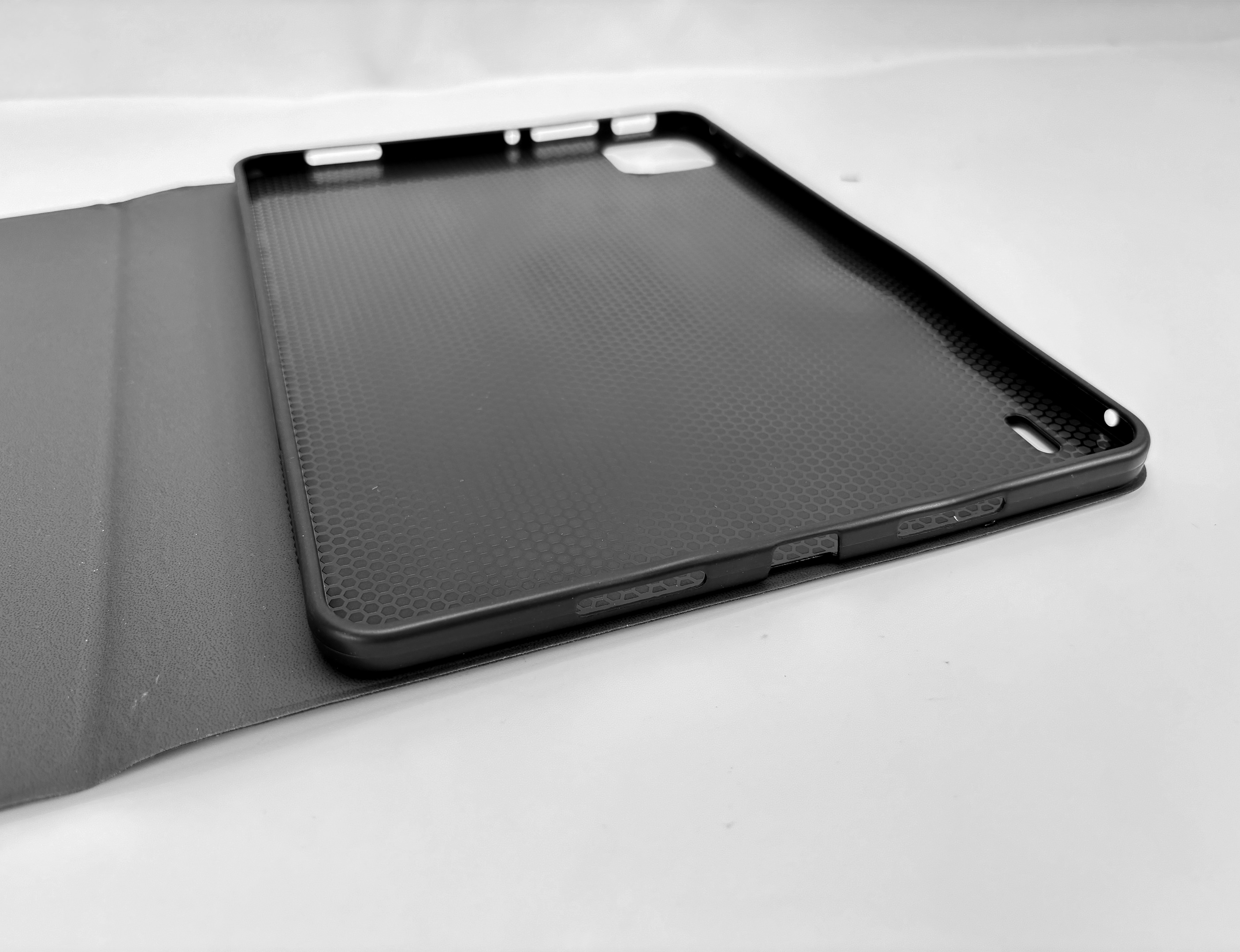 Eine schwarze Tablethülle mit strukturierter Oberfläche ist auf einer weißen Oberfläche geöffnet.