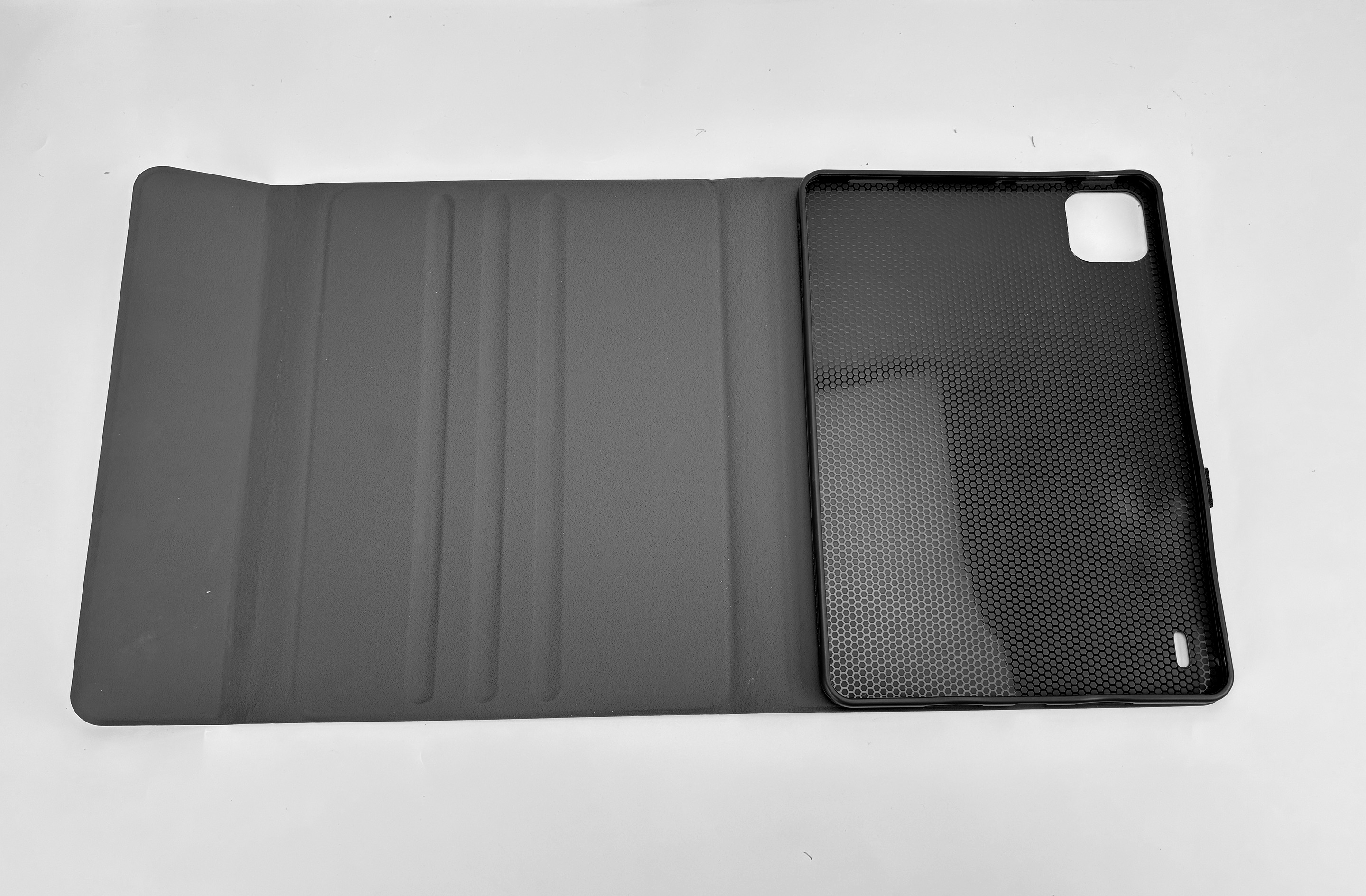 Tablet-Hülle offen, mit Tablethalter. Graue Hülle auf weißem Untergrund, schwarzer Tablethalter mit Wabenmuster.