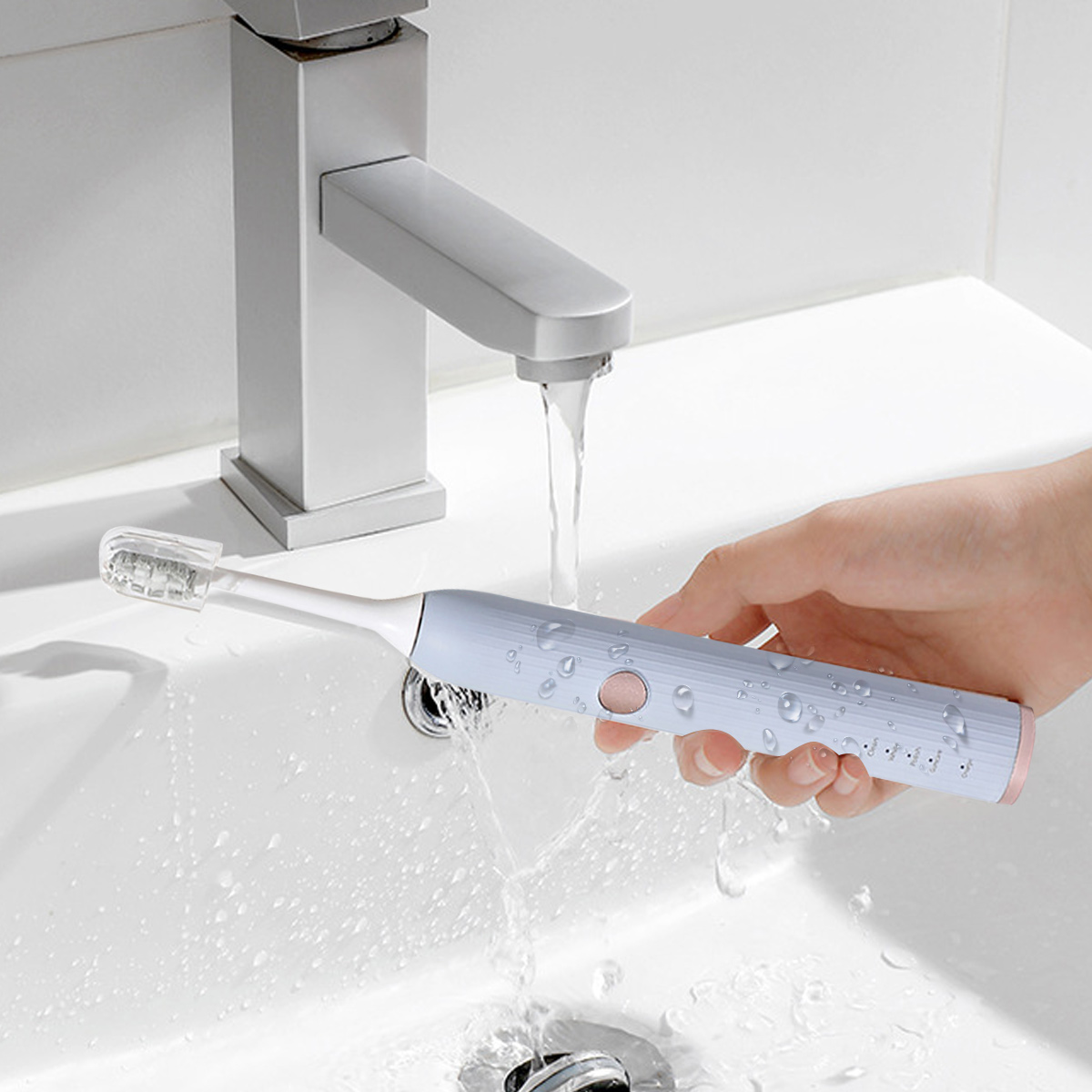 Eine Hand hält eine blaue und rosa elektrische Zahnbürste unter fließendem Wasser aus einem silbernen Wasserhahn. Die Zahnbürste hat Wassertropfen.