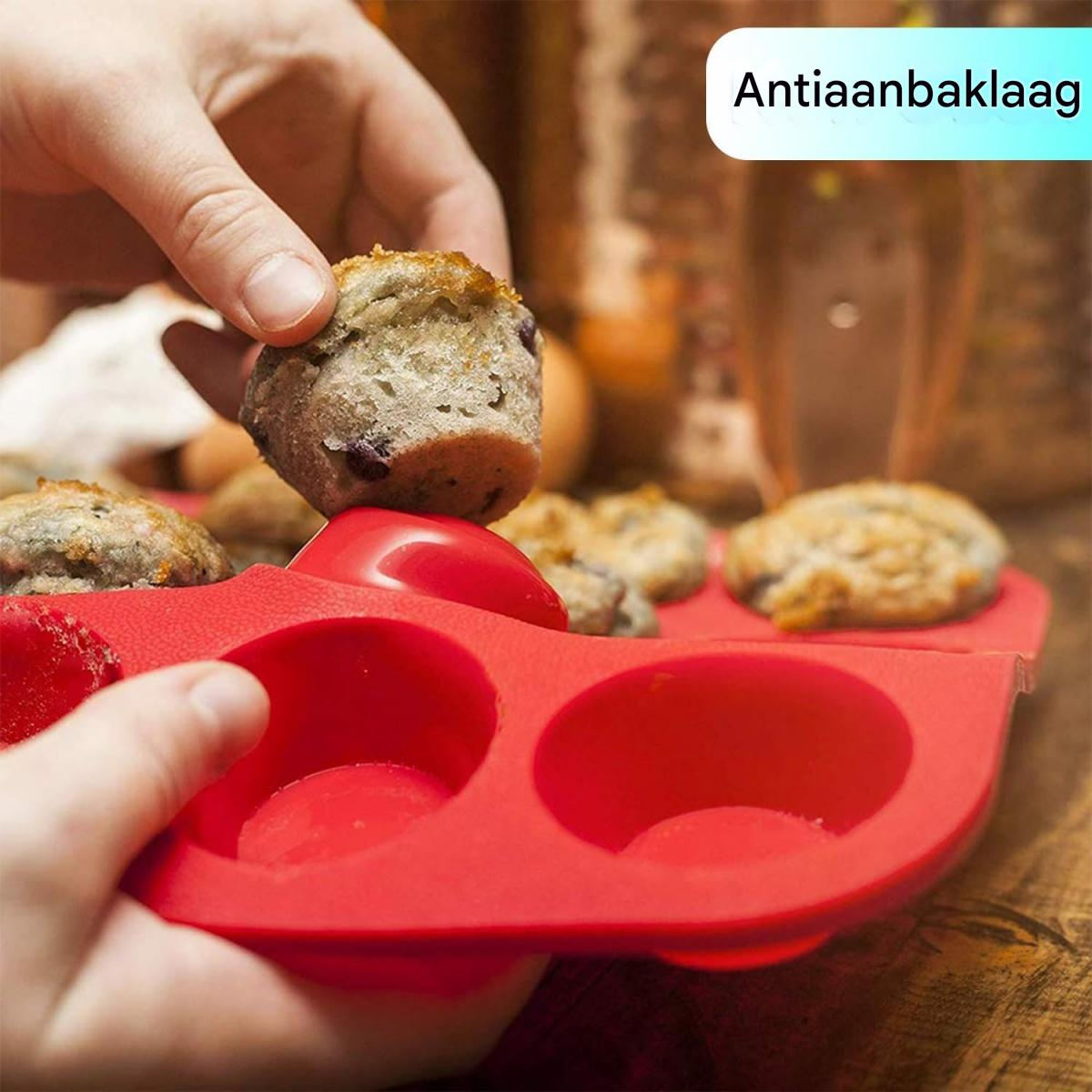 Eine Hand hält einen Muffin über einer roten Silikonform. Andere Muffins sind sichtbar, zusammen mit dem Text 'Antiaanbaklaag'.