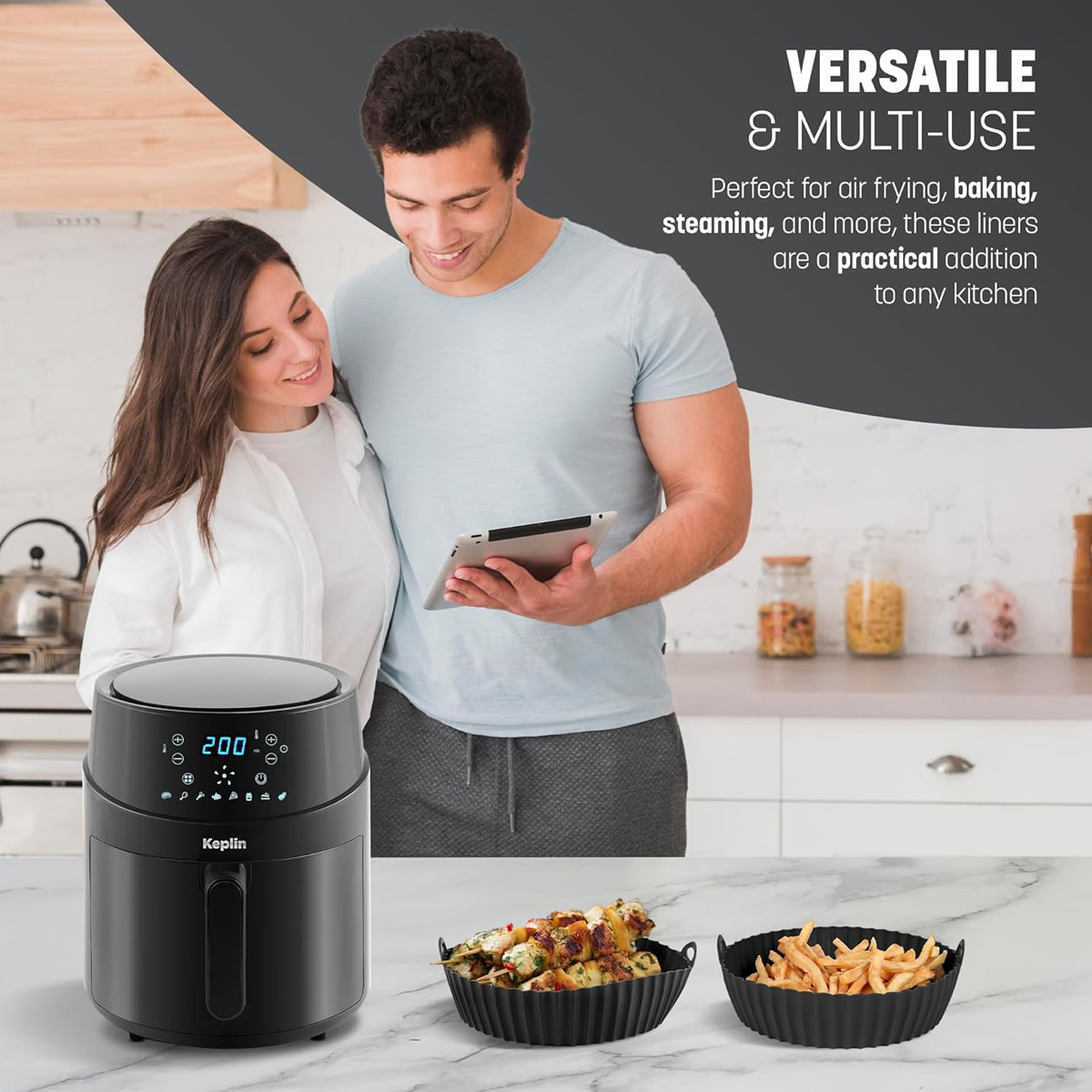 Ein Paar betrachtet eine Heißluftfritteuse. Die Fritteuse ist schwarz mit digitaler Anzeige. Es gibt auch zwei schwarze Körbe mit Essen.