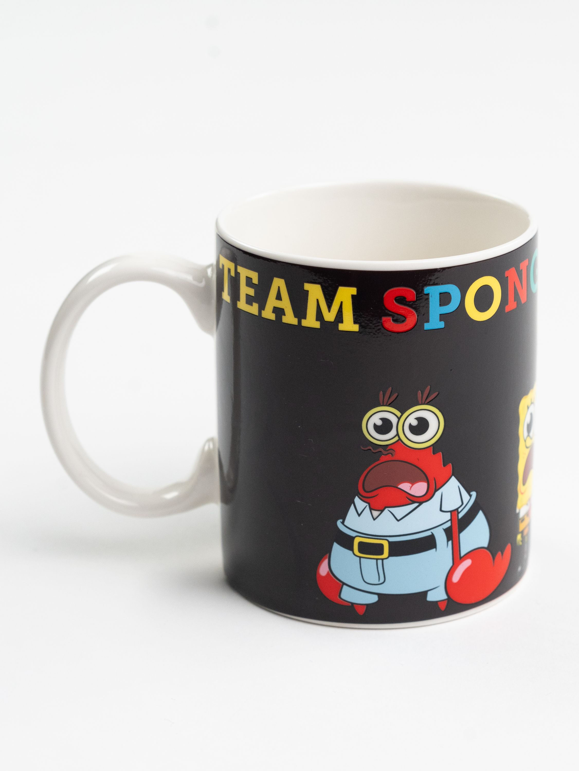Eine Tasse mit "TEAM SPONGEBOB" darauf, mit Mr. Krabs und SpongeBob, vor schwarzem Hintergrund.
