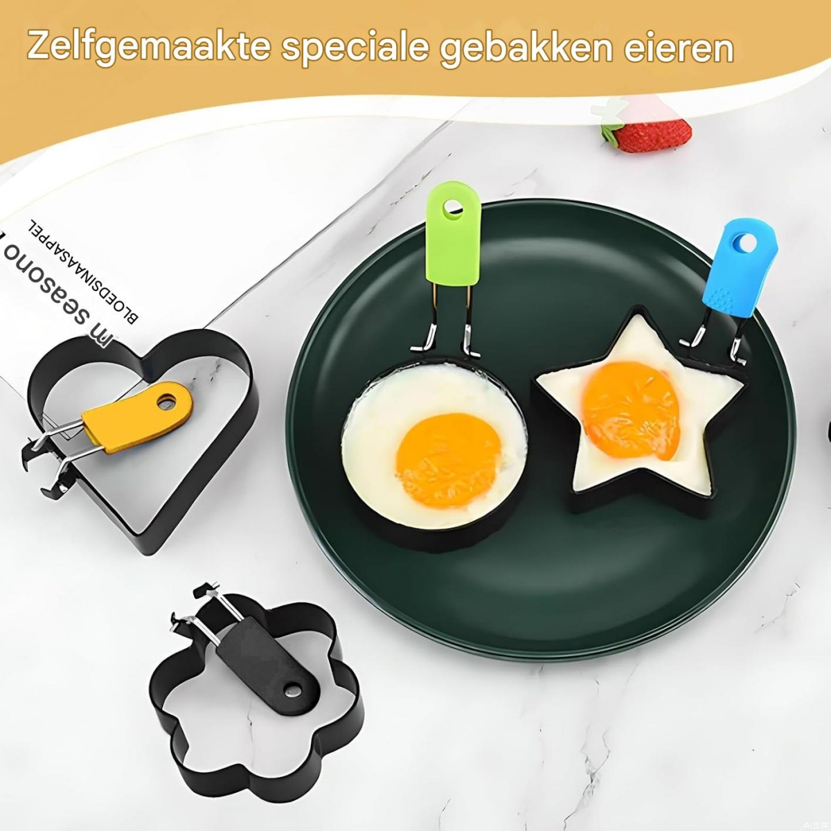 Spiegeleier in Herz- und Sternform auf einem grünen Teller. Eierformer aus schwarzem Metall. Gelbe, grüne und blaue Griffe.