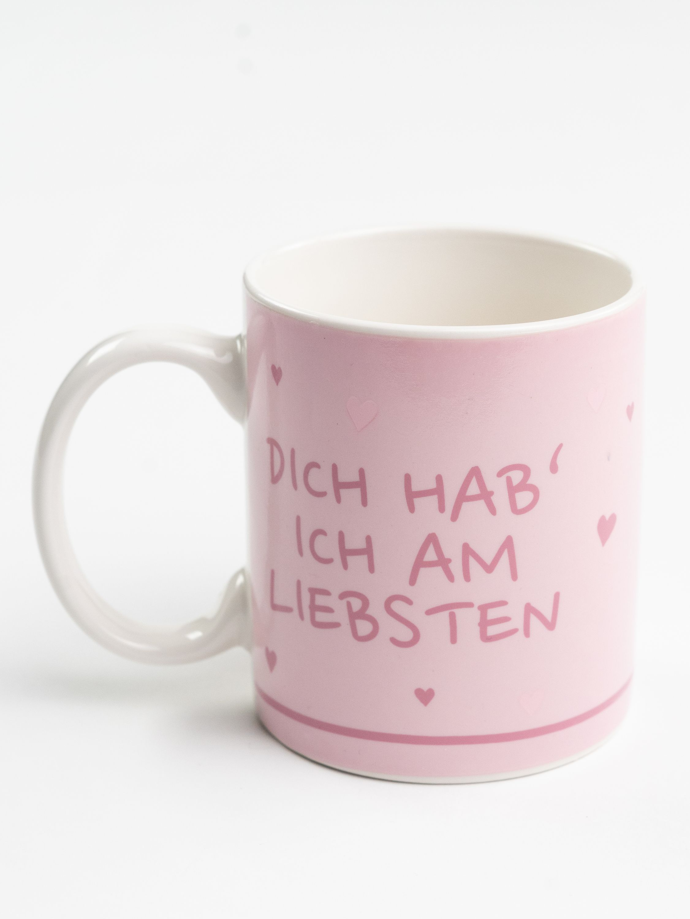 Rosa Tasse mit weißem Henkel, Text 'Dich hab ich am liebsten', kleine Herzen, auf weißem Hintergrund.
