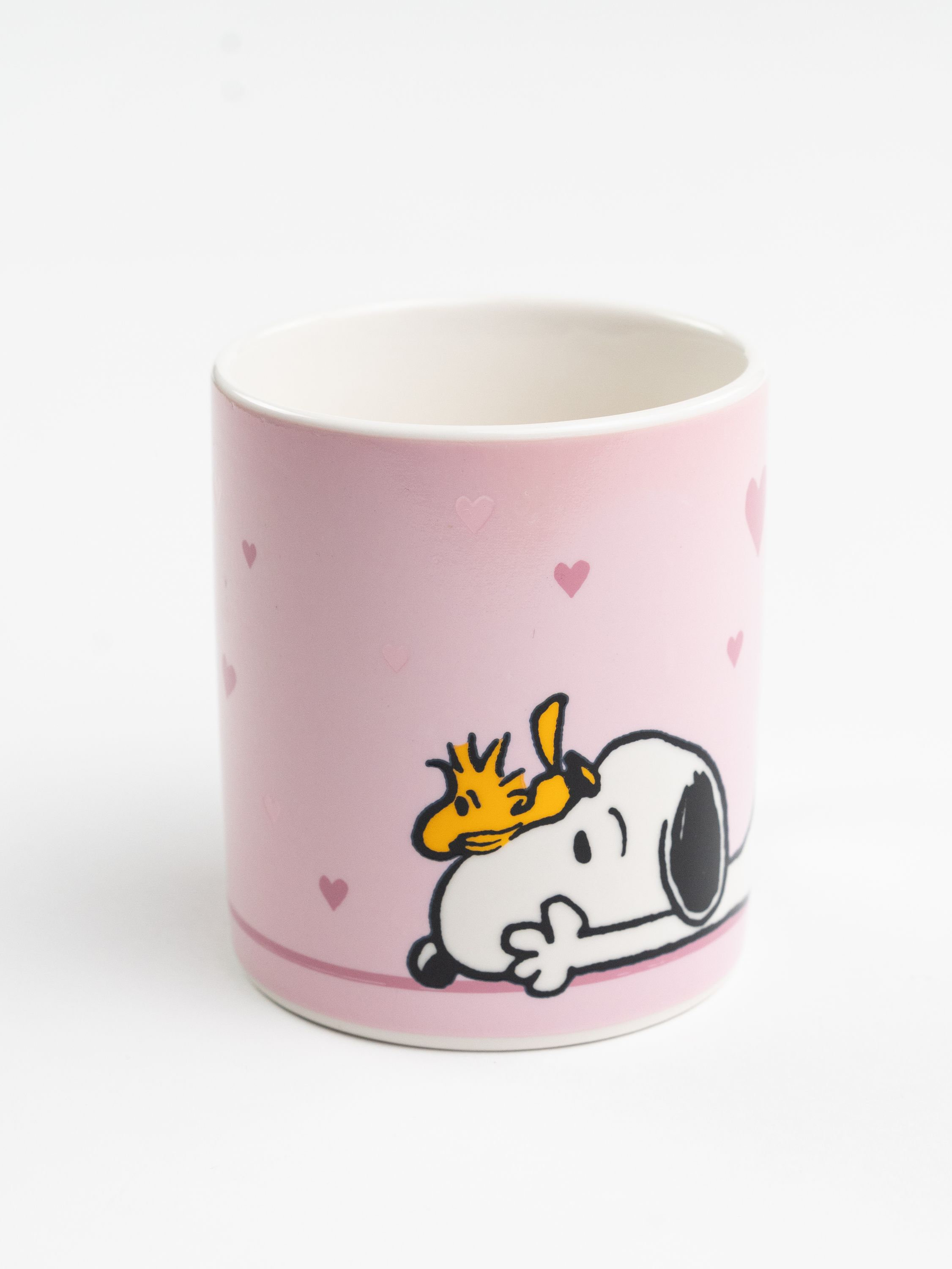 Eine rosa Tasse mit Herzen, Snoopy und Woodstock. Snoopy liegt. Woodstock sitzt auf Snoopy's Kopf.