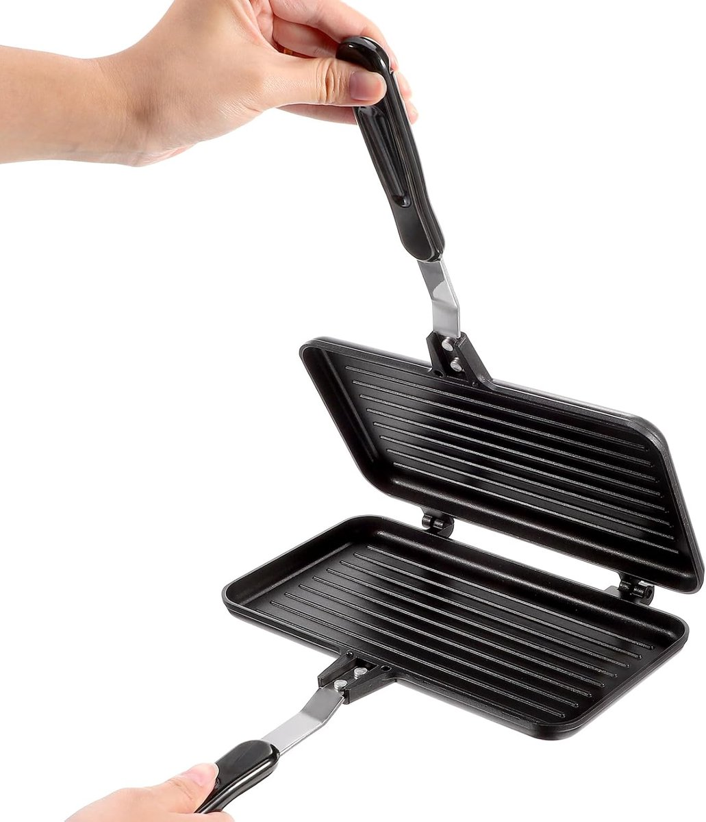 Eine Person hält einen offenen, schwarzen Sandwichmaker. Der Sandwichmaker hat eine gerippte Oberfläche. Der Hintergrund ist weiß.