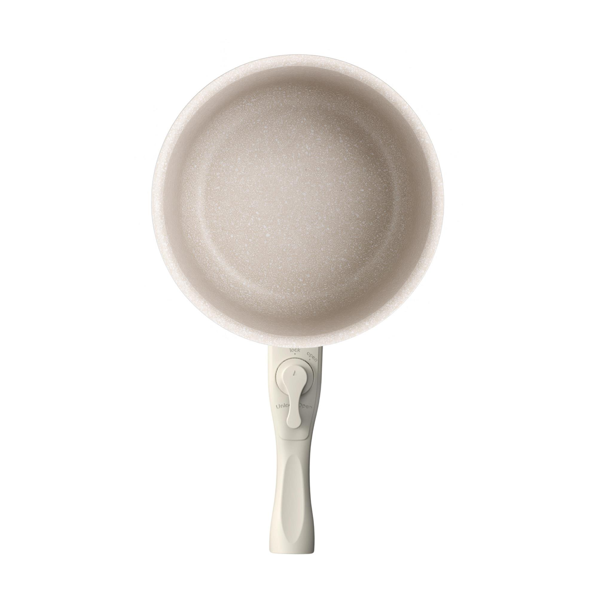 Vista superior de una sartén beige claro con un mango largo. El mango tiene un dial para abrir y cerrar.