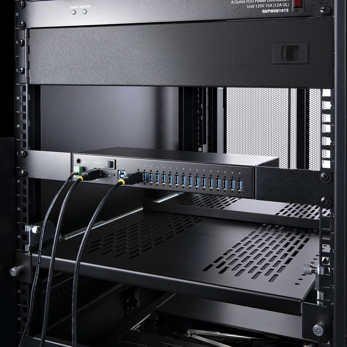 Ein schwarzer Serverschrank mit einem USB-Hub und angeschlossenen Kabeln. Ein Regal und eine Stromverteilungseinheit sind ebenfalls sichtbar.