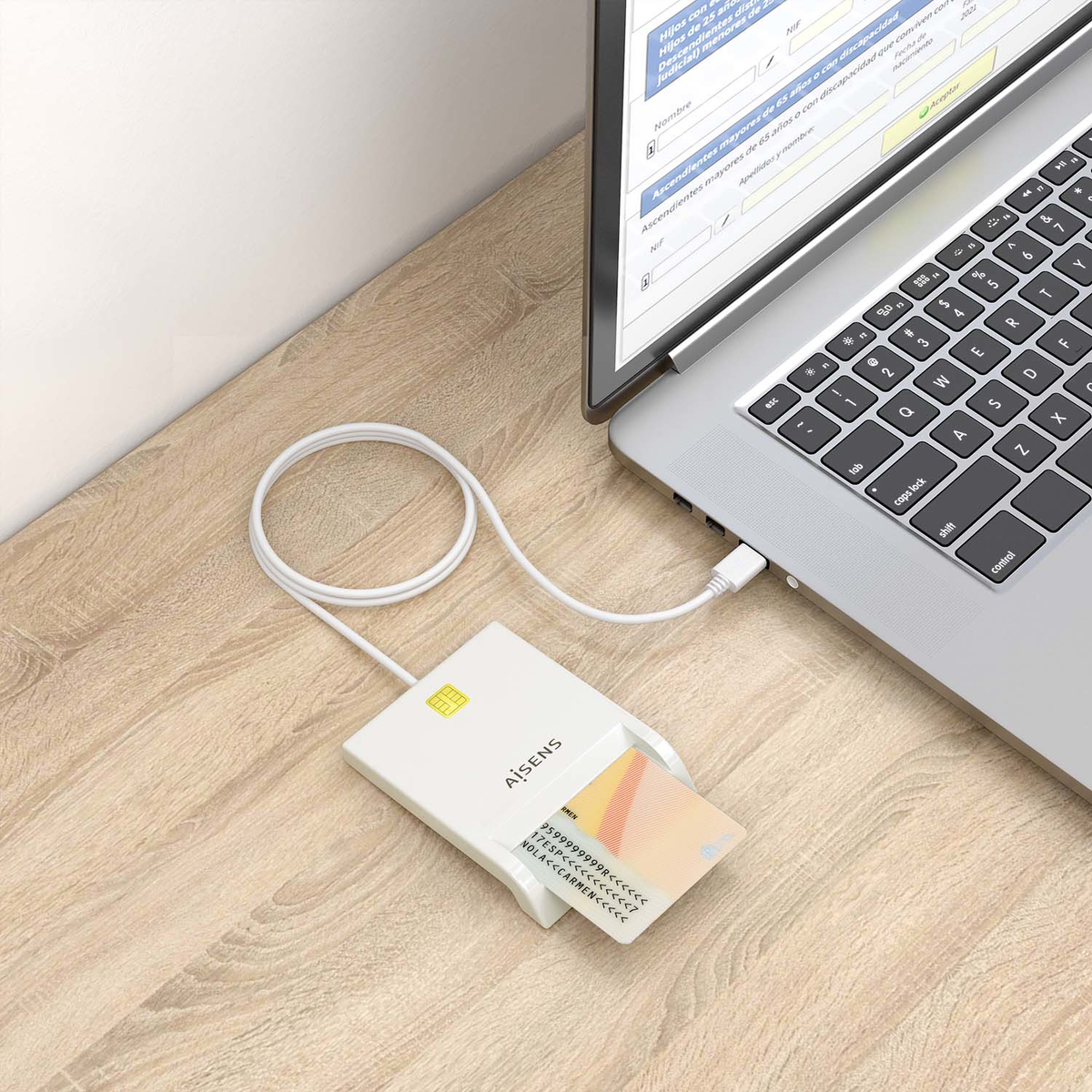 Un lector de tarjetas blanco con una tarjeta insertada está conectado a una computadora portátil a través de un cable USB. La computadora portátil muestra un formulario.