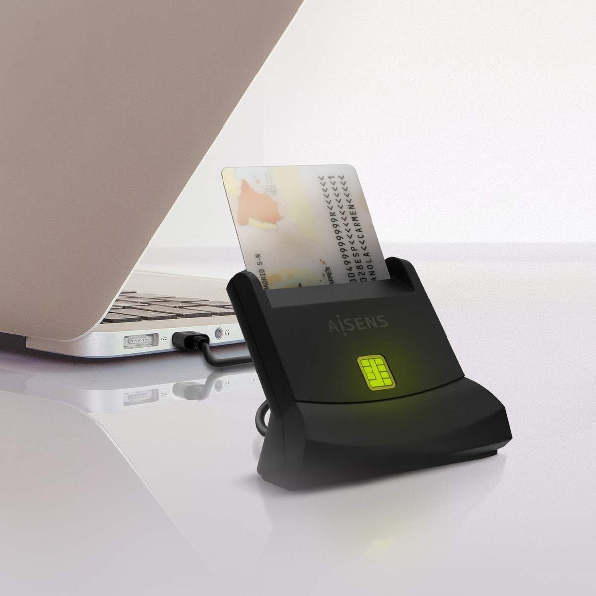 Un lector de tarjetas con una tarjeta insertada, conectado a una computadora portátil. El lector es negro y tiene una luz verde. La tarjeta tiene texto.