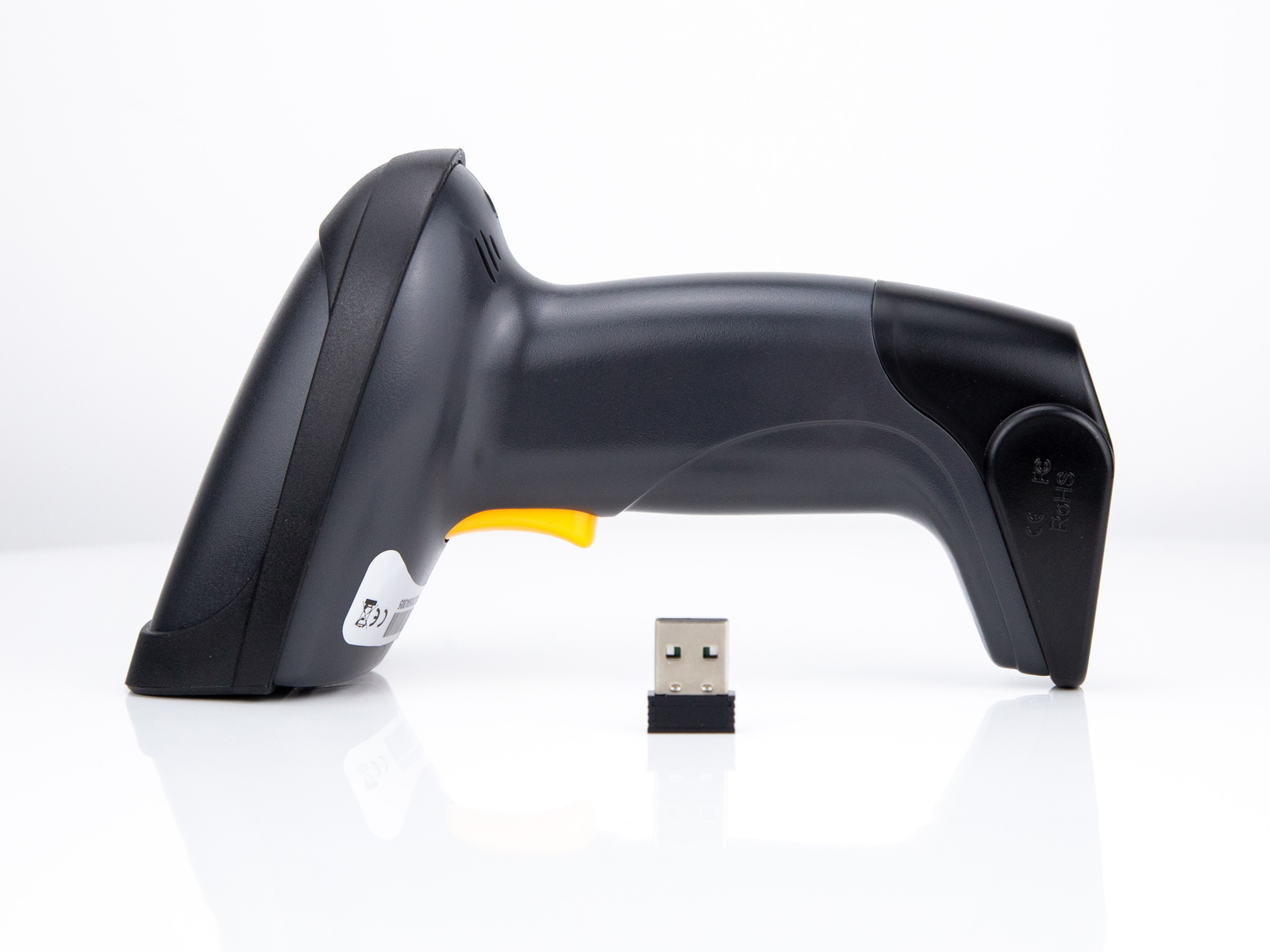 Uno scanner di codici a barre portatile, nero con grilletto giallo, è posizionato accanto a un dongle USB, il tutto su una superficie bianca riflettente.