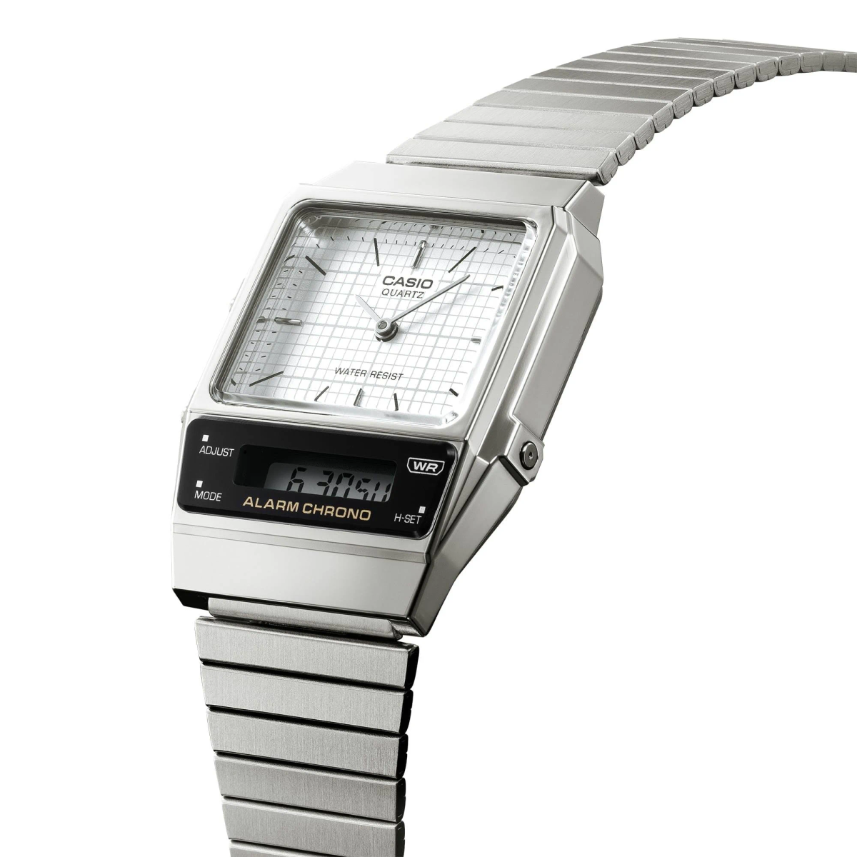 Un reloj Casio plateado con esfera blanca y pantalla digital. El reloj tiene una correa de metal y está sobre un fondo blanco.