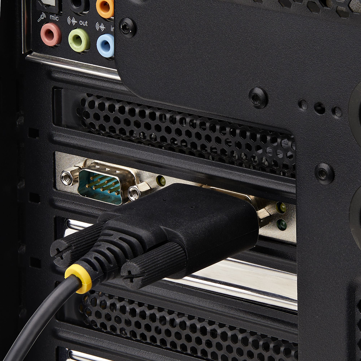 Primer plano del panel trasero de una computadora. Un cable negro está conectado a un puerto. Puertos de audio visibles. La carcasa es negra.