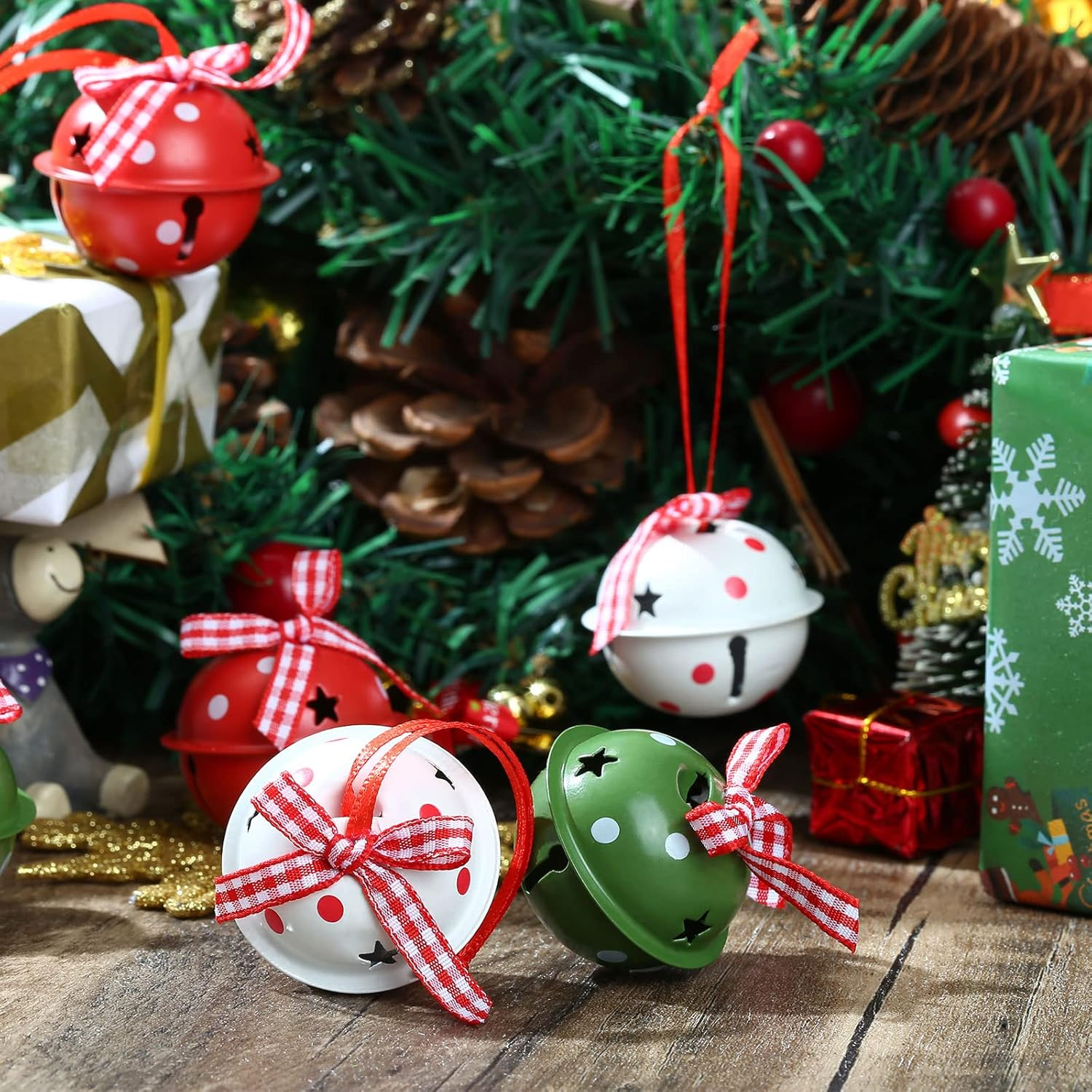 Weihnachtsschmuck: Rote, weiße und grüne Glocken mit roten Bändern, vor einem Weihnachtsbaumhintergrund und Geschenken.