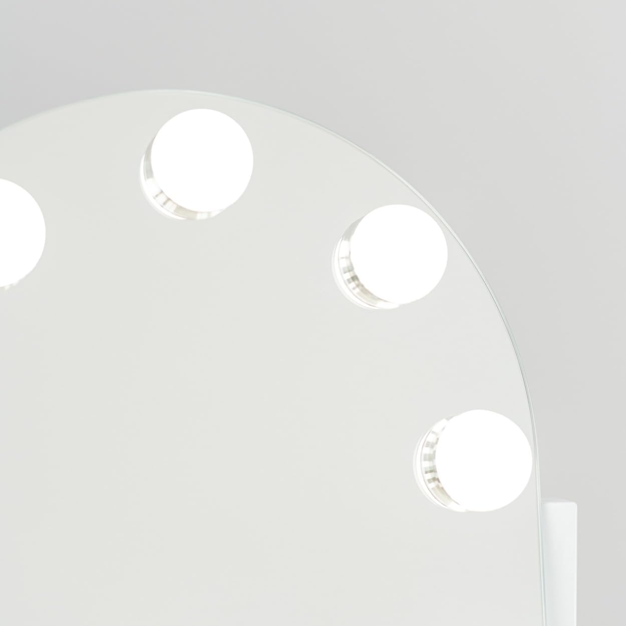 Primer plano de un espejo de tocador blanco con cinco luces redondas y brillantes. El fondo es blanco liso.