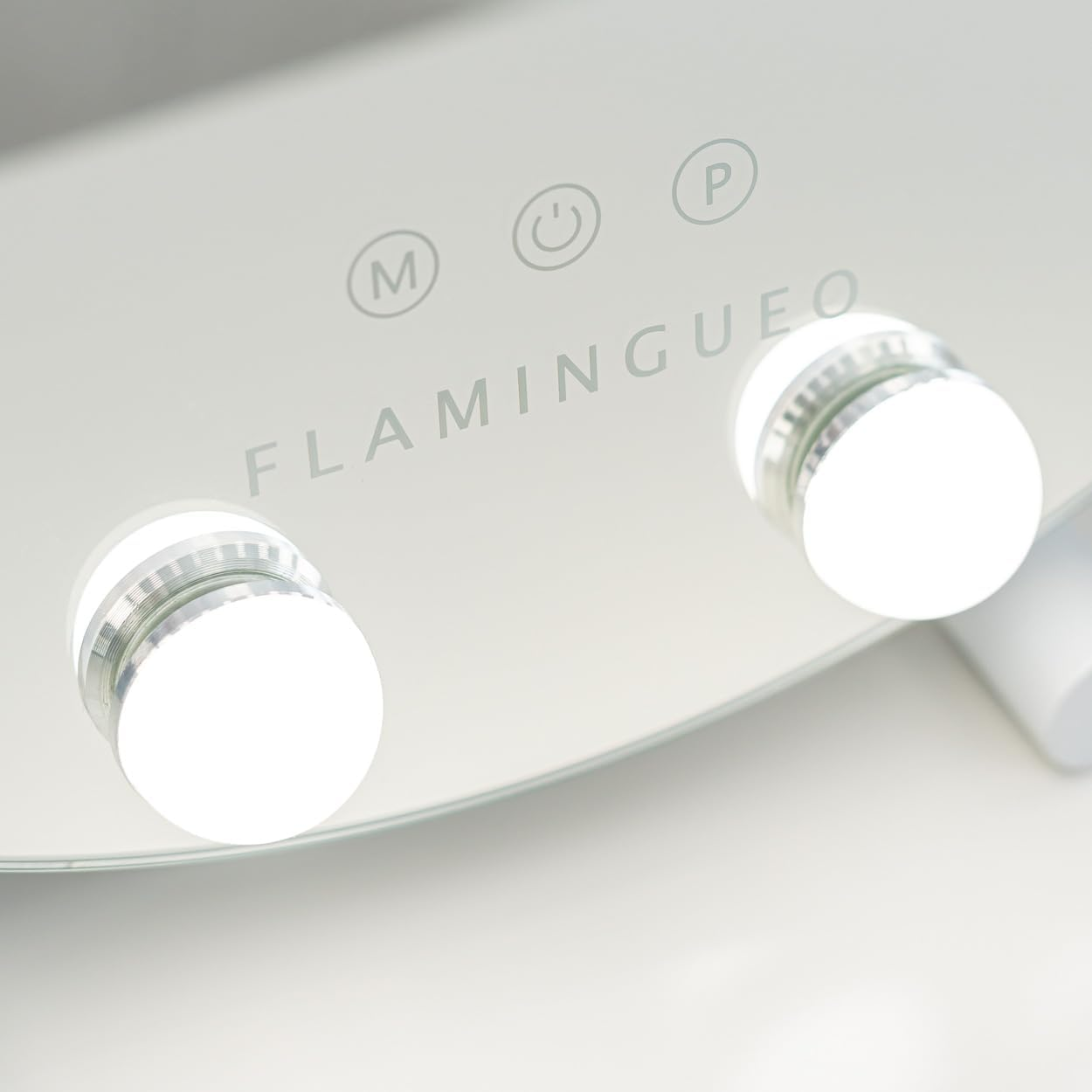Un espejo de maquillaje blanco con dos luces brillantes. Controles y la marca 'Flamingueo' son visibles.