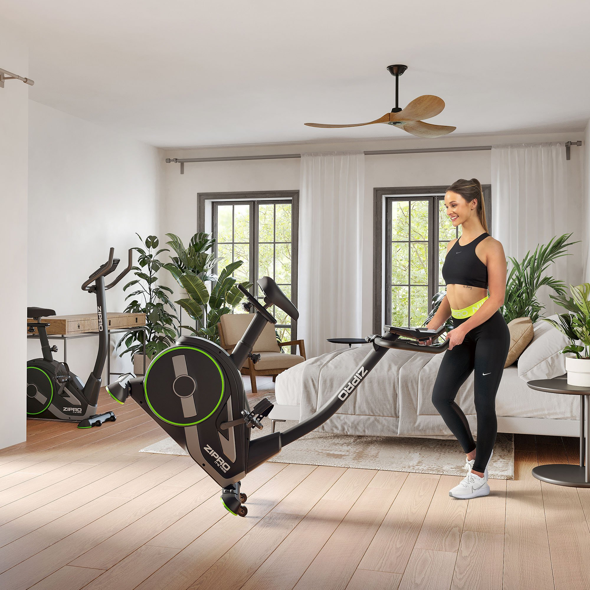 Mujer con máquina de fitness en una habitación. Cama y plantas al fondo.