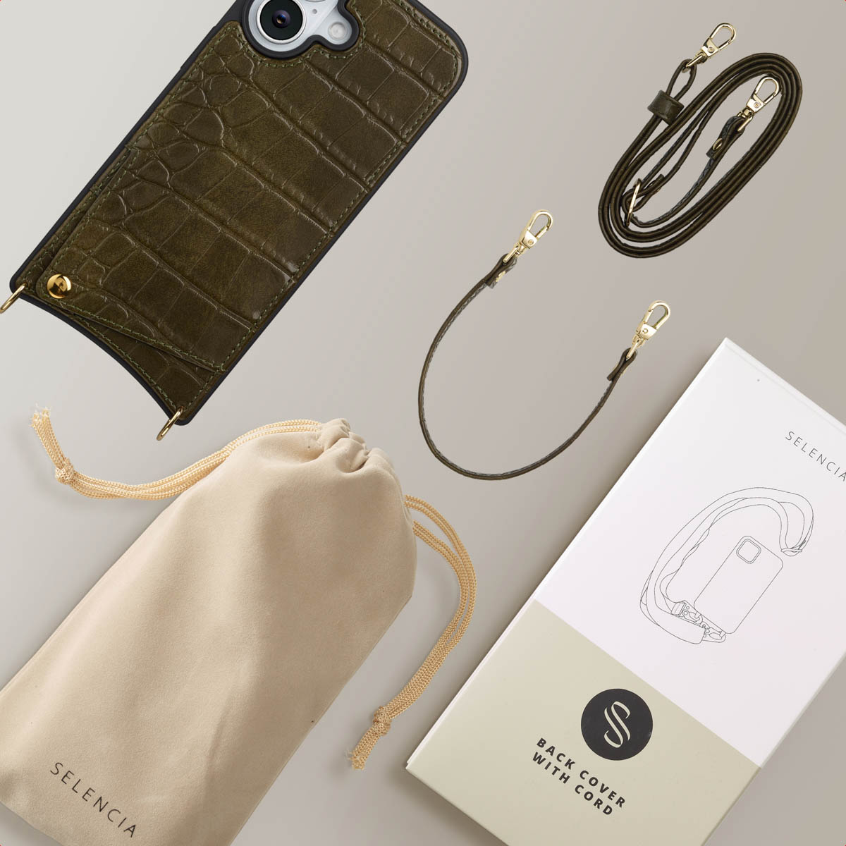 Olijfgroene telefoonhoes, koord en tas op een licht oppervlak. Er is ook een doos met een telefoonillustratie.