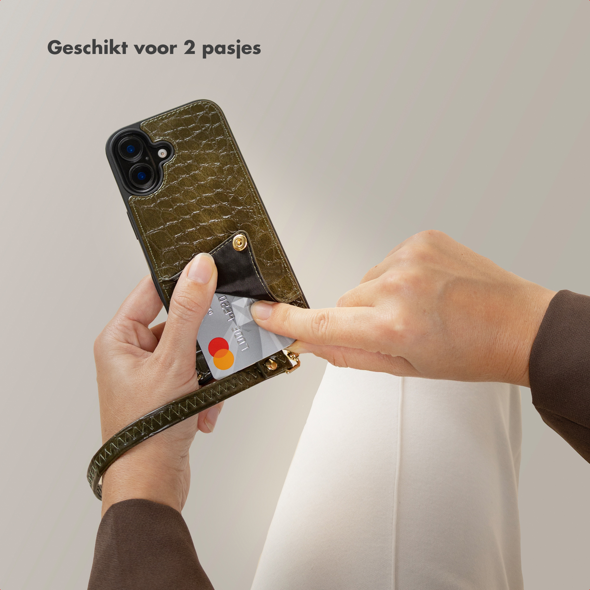 Een hand houdt een telefoonhoesje vast met een kaart die wordt ingevoegd. De hoes is groen met een polsbandje.