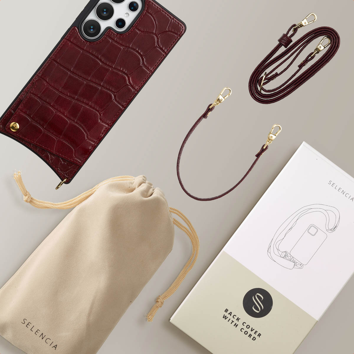 Vue aérienne d'un étui de téléphone, d'une sangle et d'un sac. L'étui est bordeaux, la sangle marron et le sac beige.