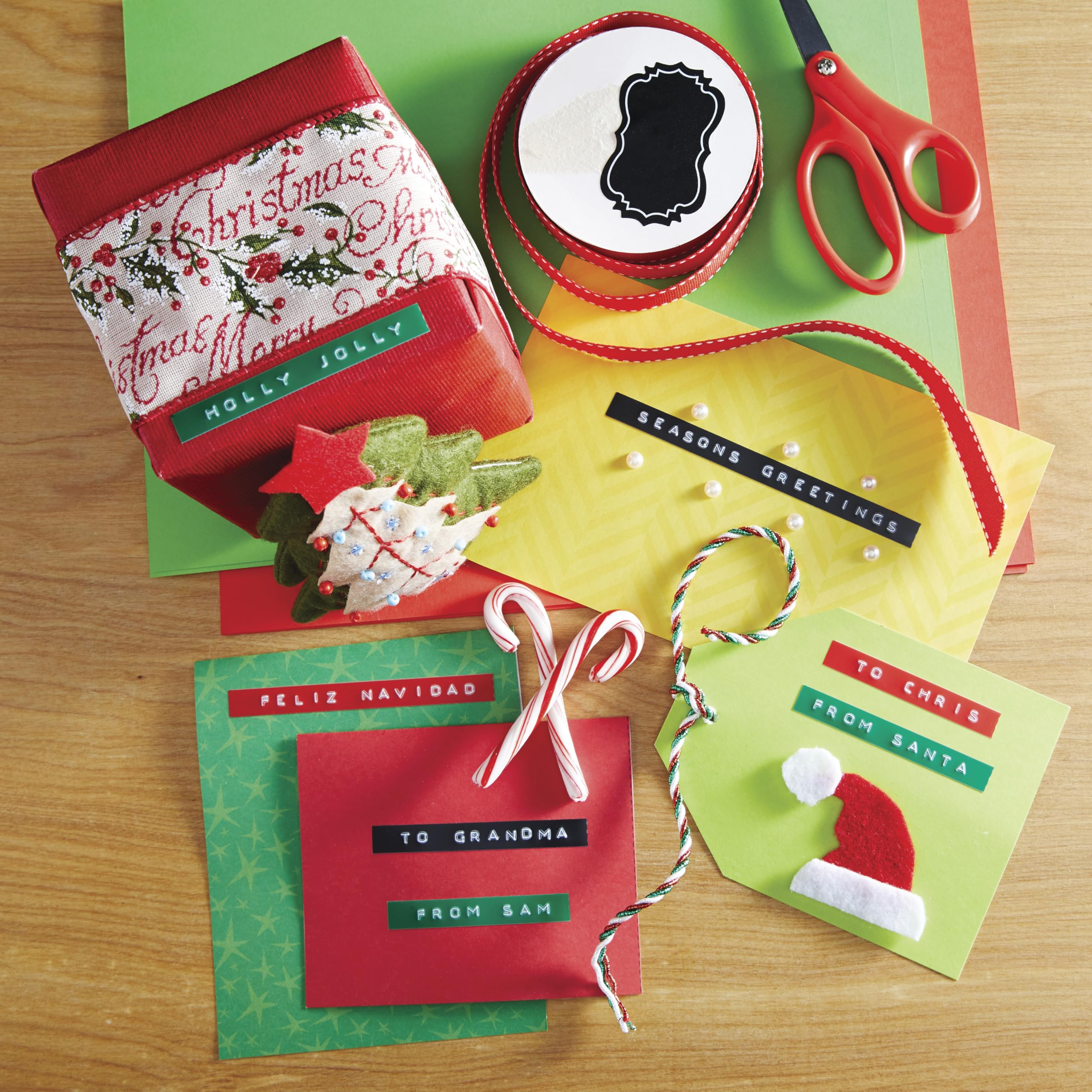 Weihnachtliches Arrangement: Geschenkbox, Karten, Bänder, Schere und Zuckerstangen auf Holzoberfläche.