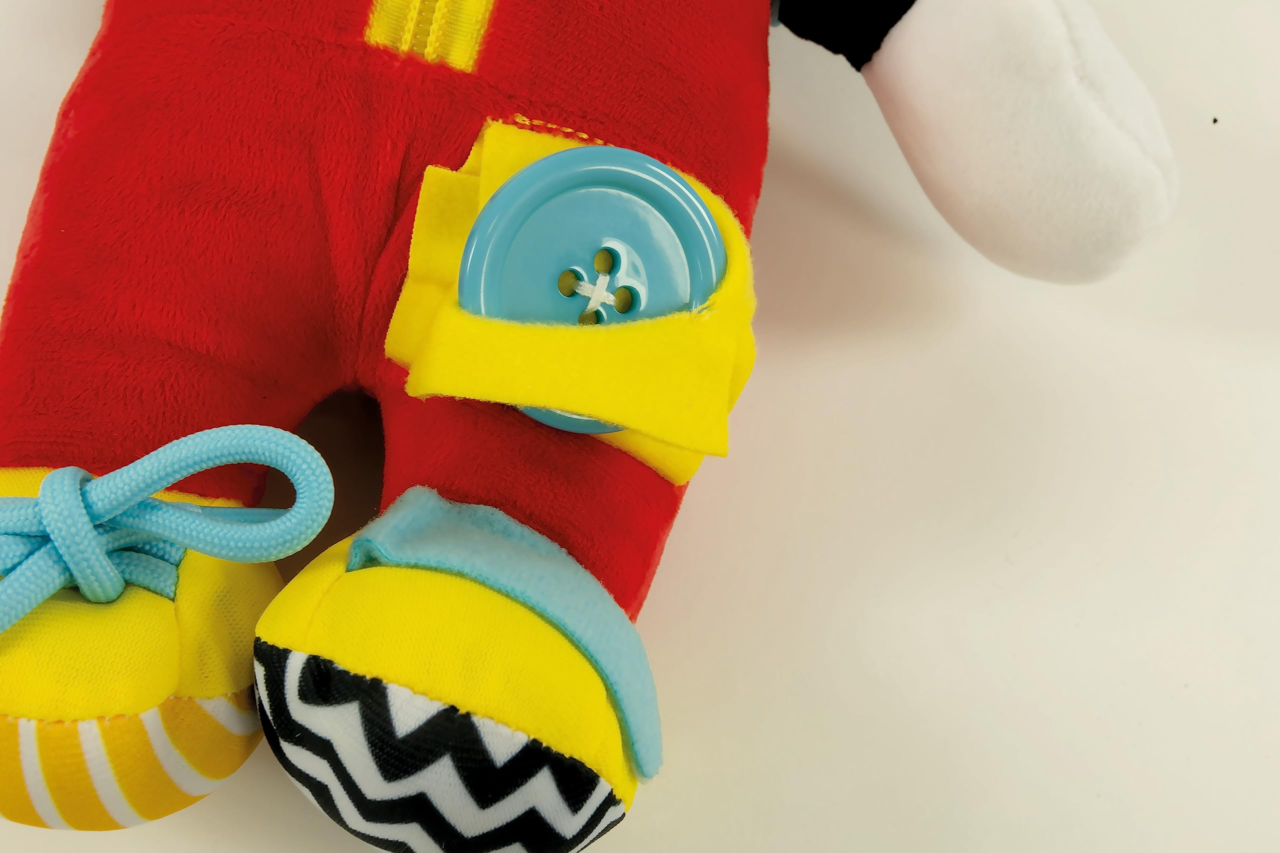 Ein Mickey-Mouse-Plüschtier. Das Spielzeug hat eine rote Hose mit blauem Knopf und gelben Akzenten. Weißer Hintergrund.